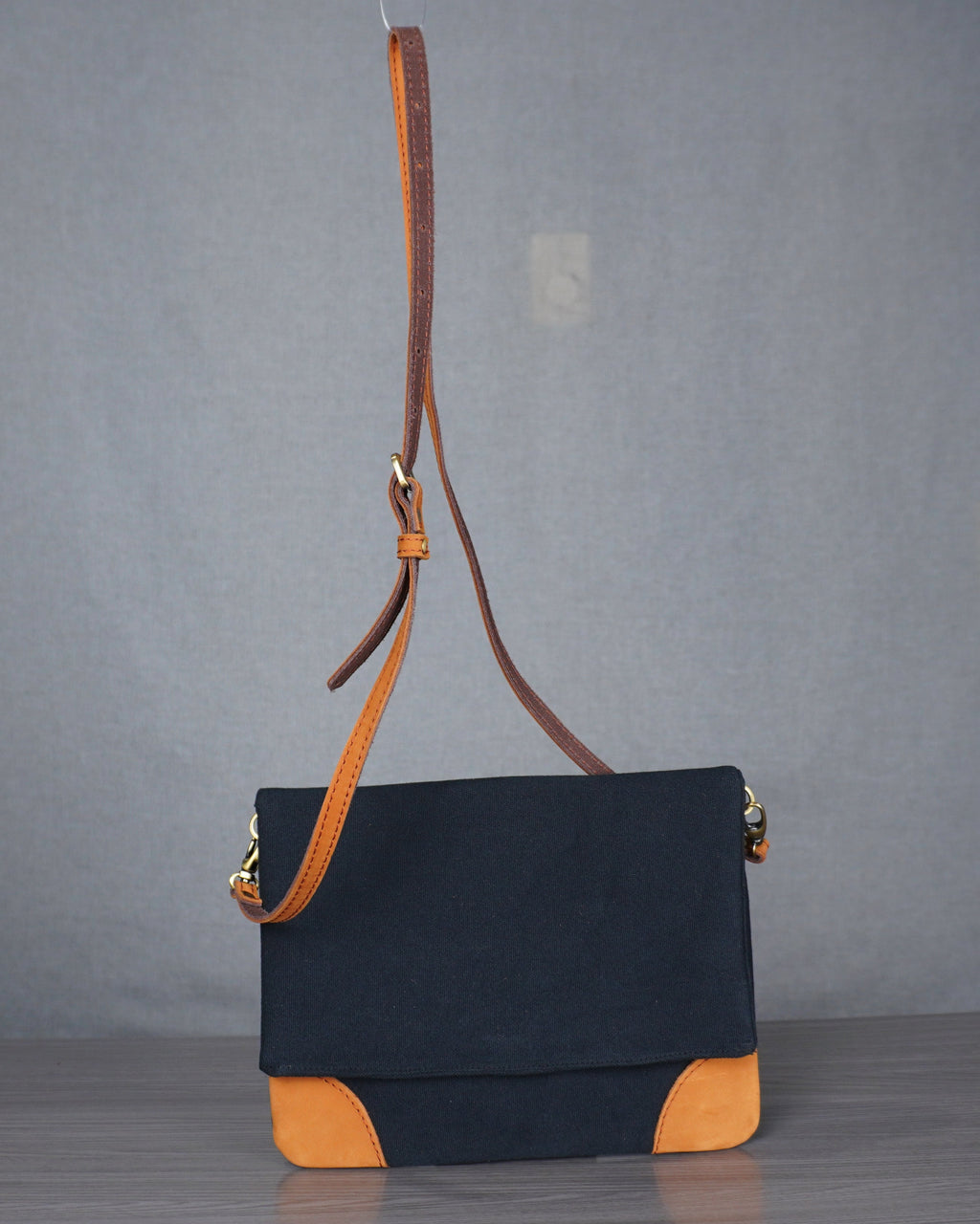 Black and orange leather handbag on a gray floor with a plain backdrop