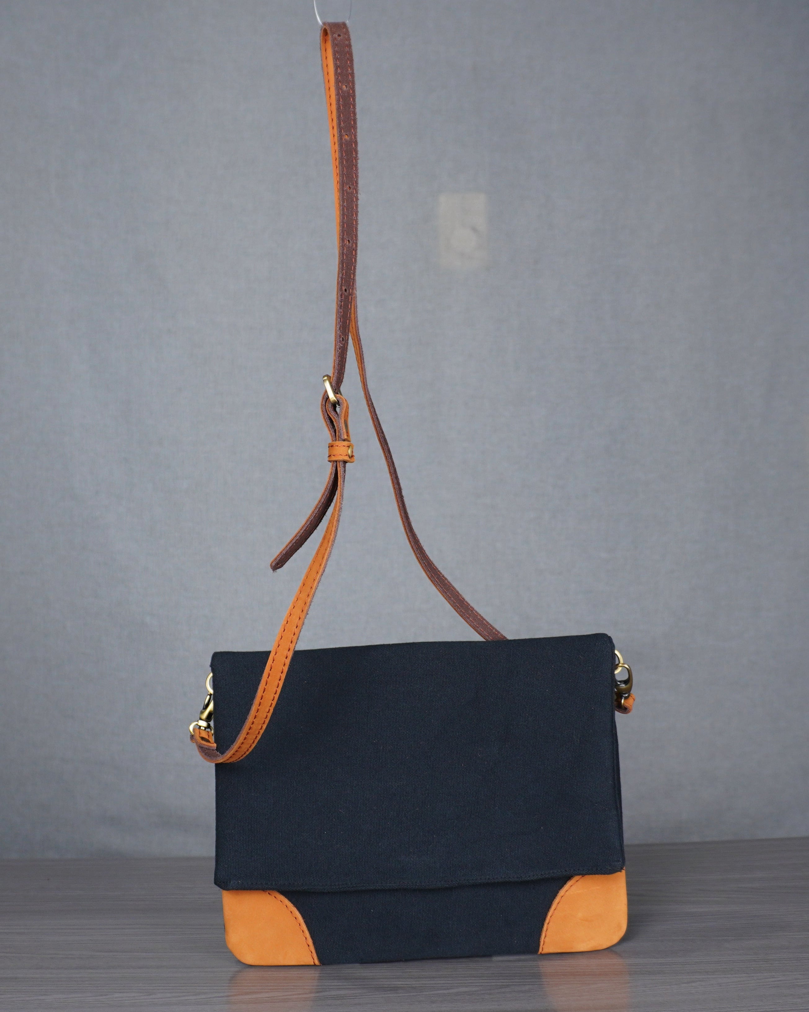 Black and orange leather handbag on a gray floor with a plain backdrop