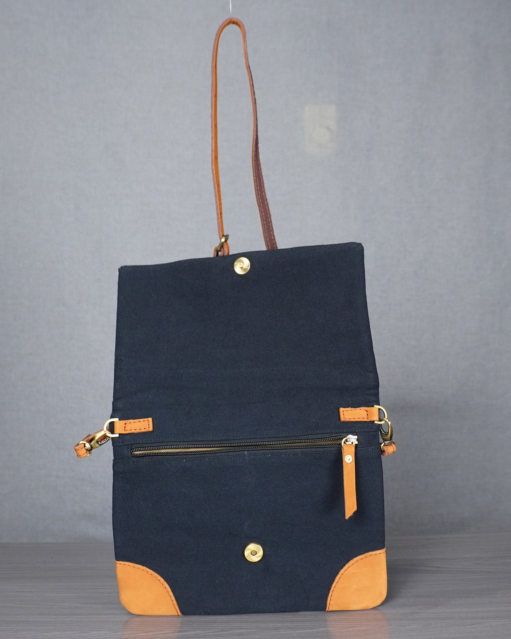 Black handbag with gold accents on a gray background