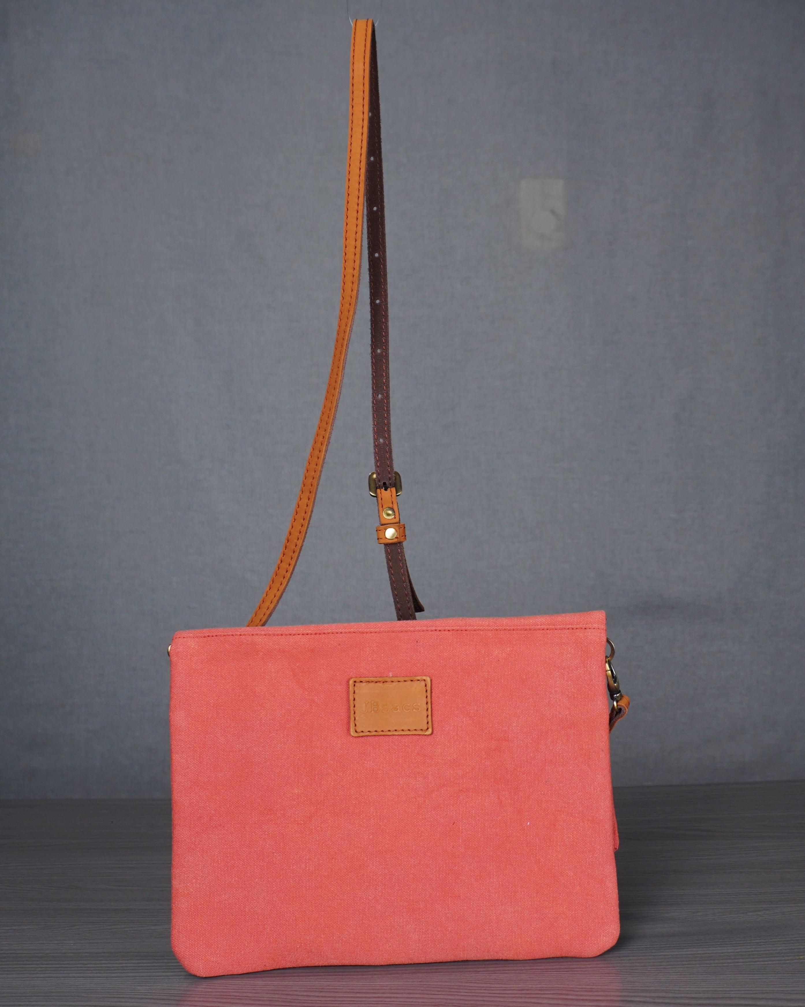 Pink handbag with a brown strap on a gray background