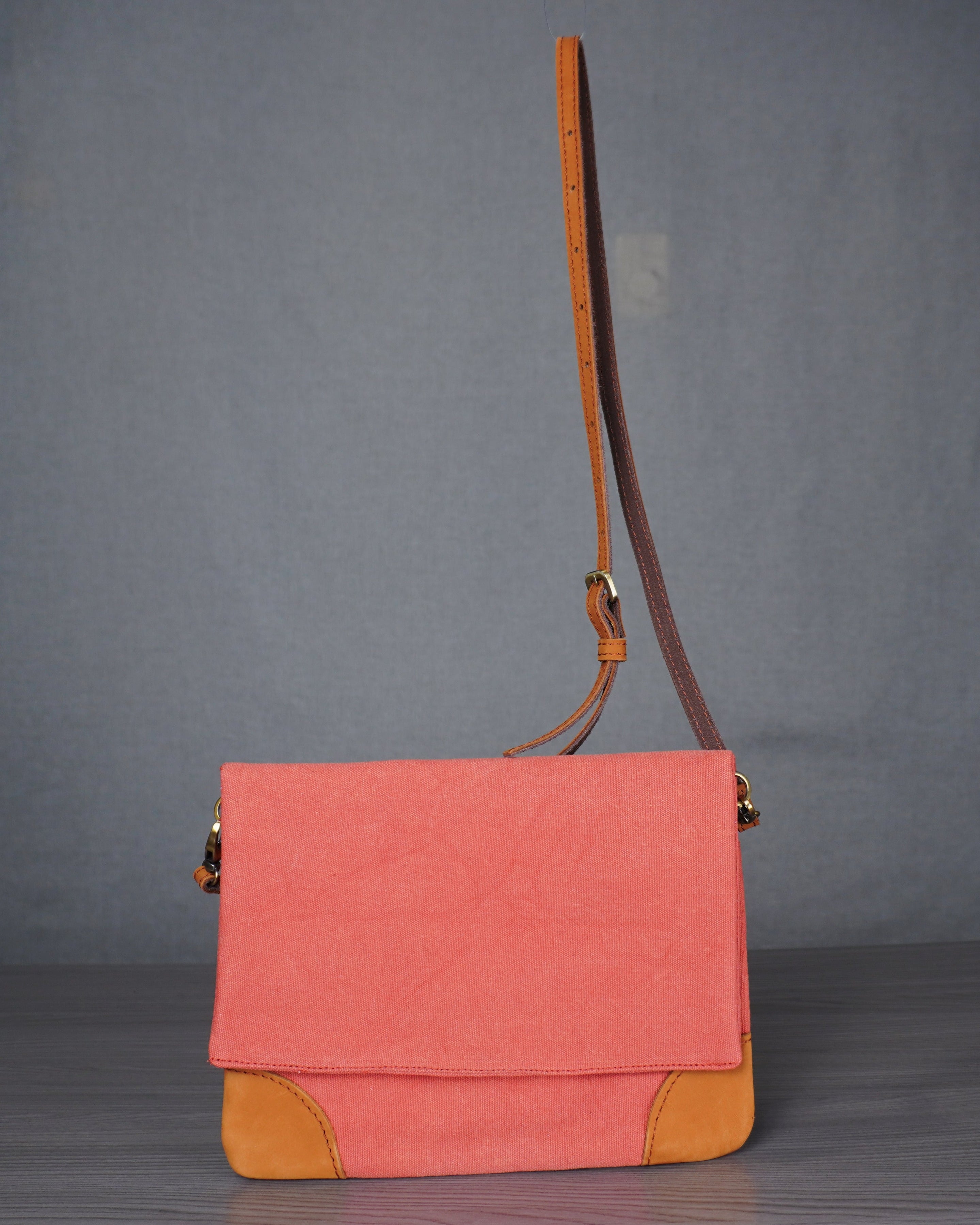 Pink and orange handbag on a gray floor with a plain background