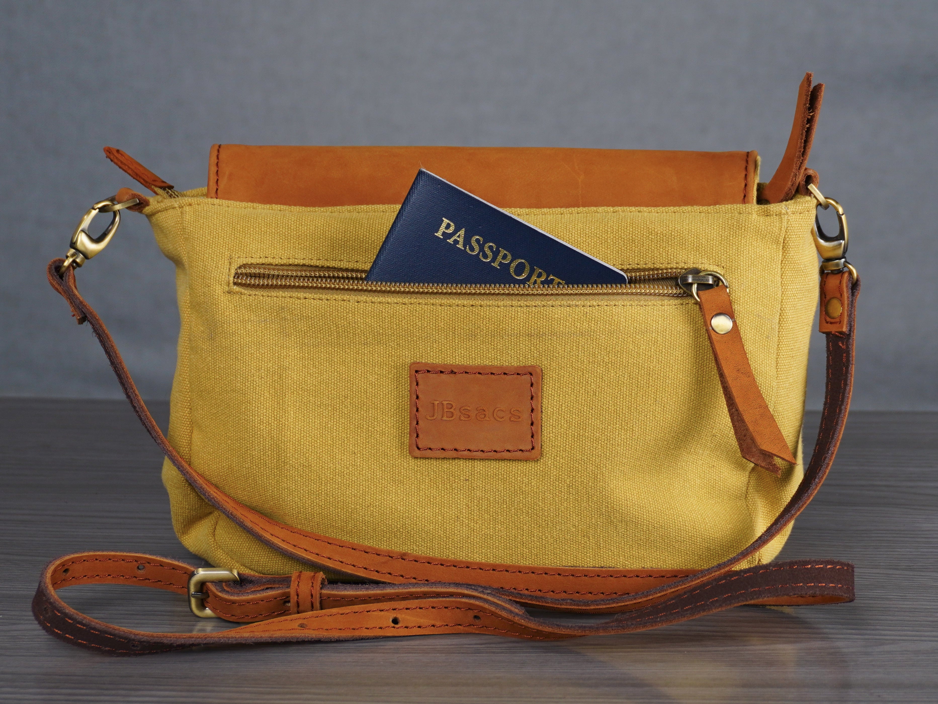 Yellow handbag with brown leather accents on a gray surface and background