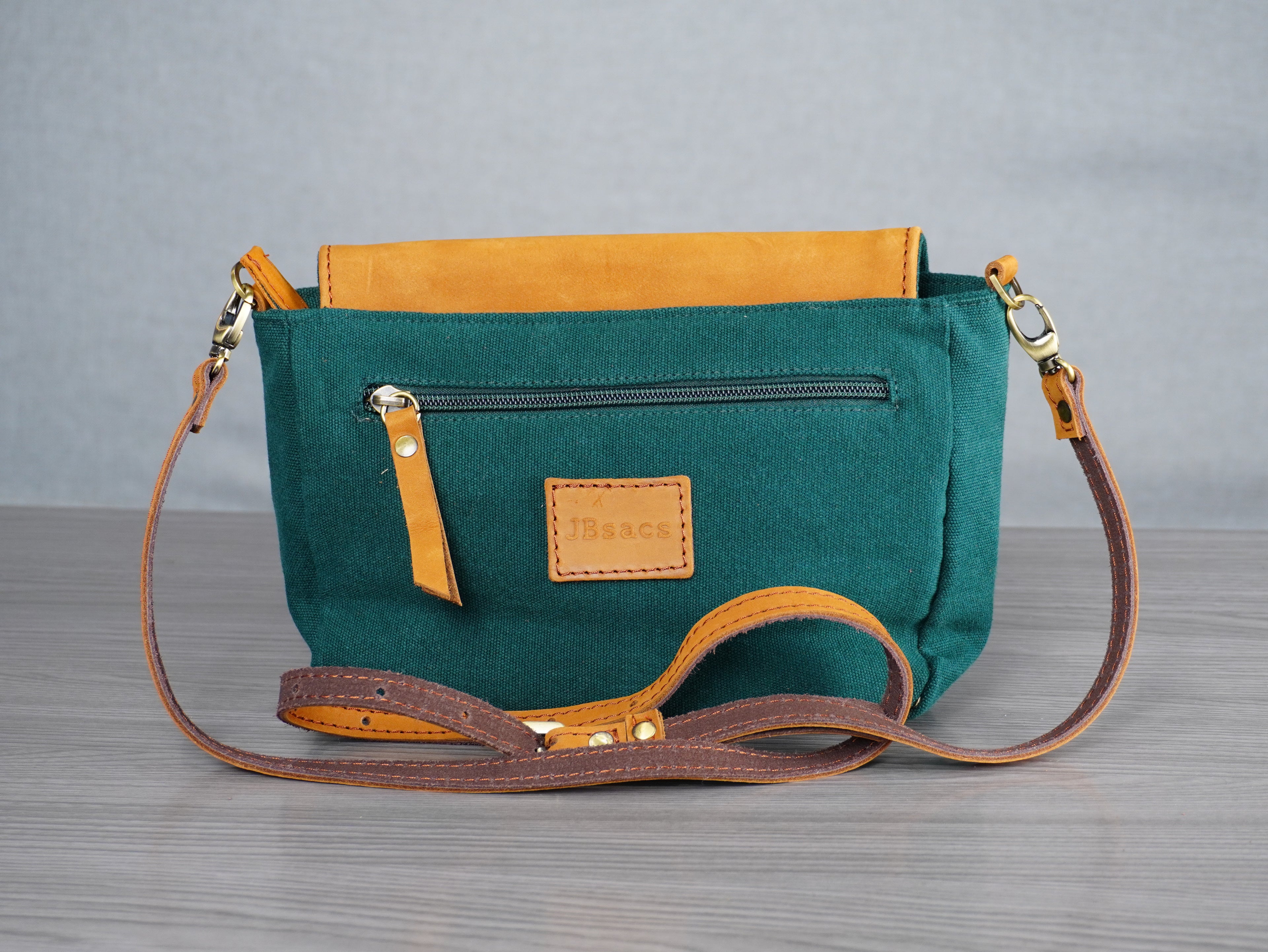 Green handbag with leather accents on a gray surface