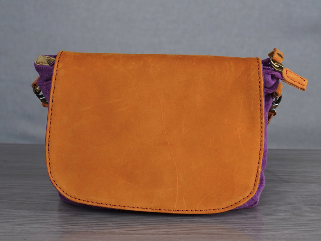 purple handbag with leather accents on a gray surface