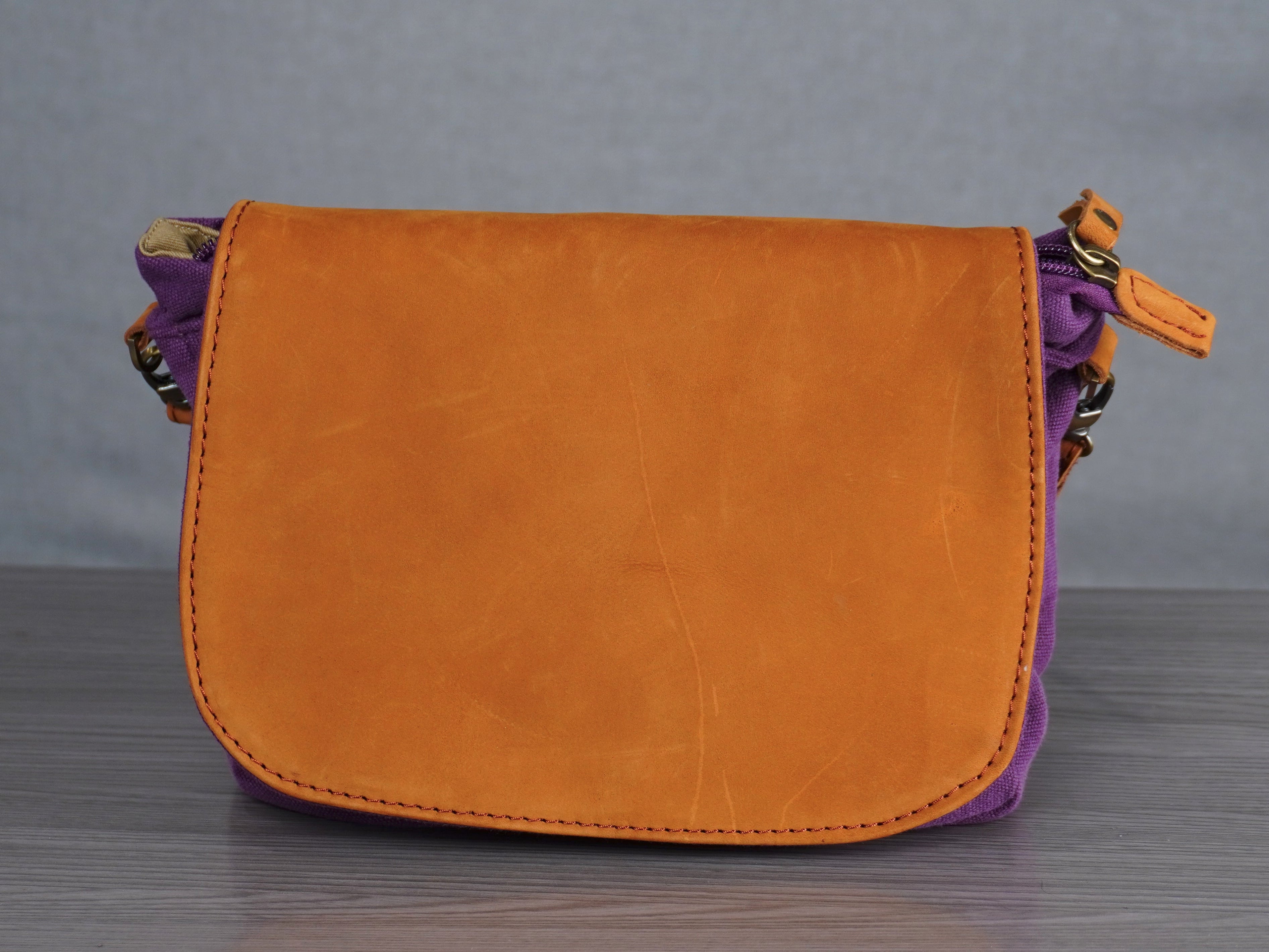 purple handbag with leather accents on a gray surface