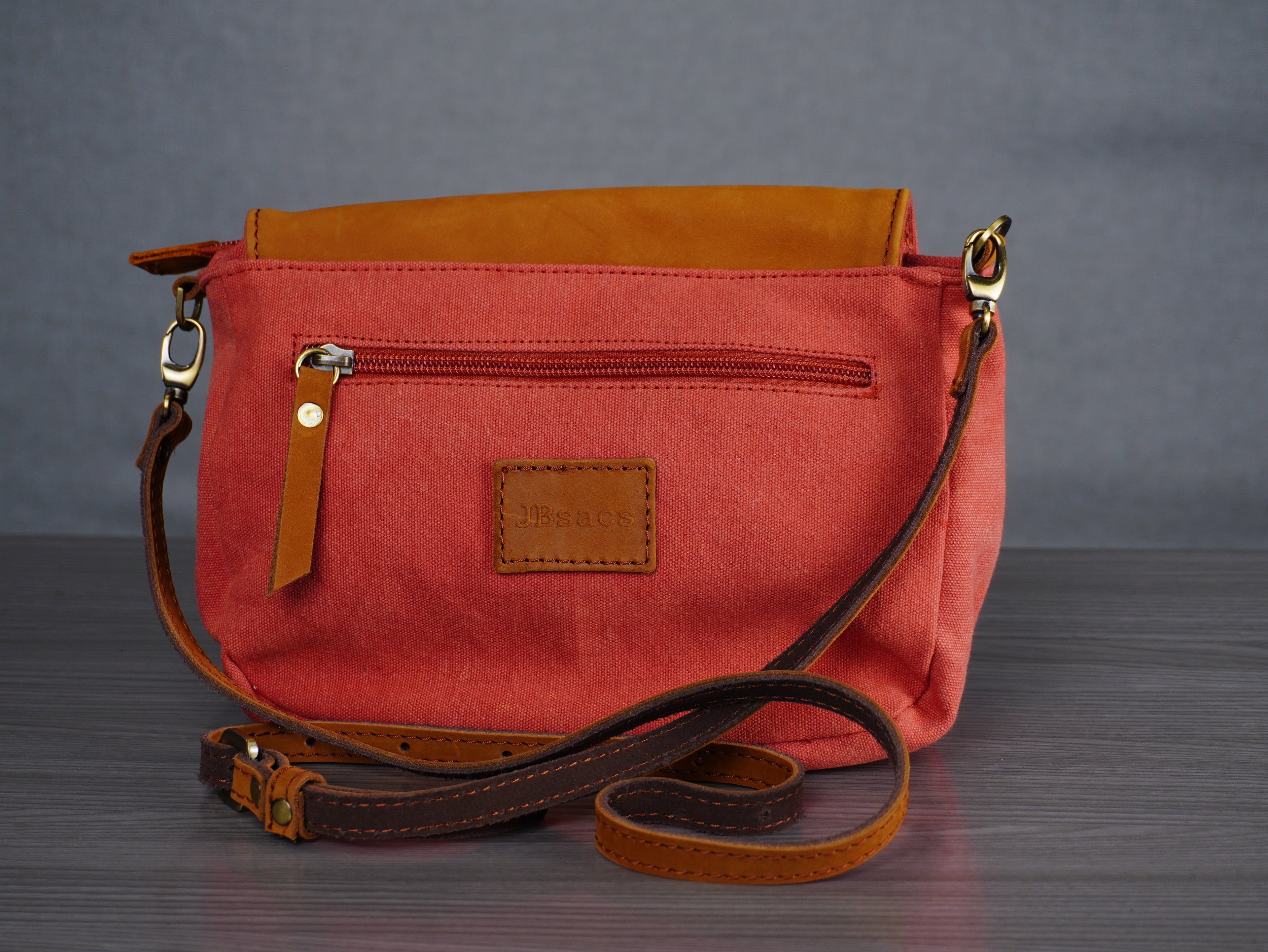 Red handbag with brown leather accents on a gray background
