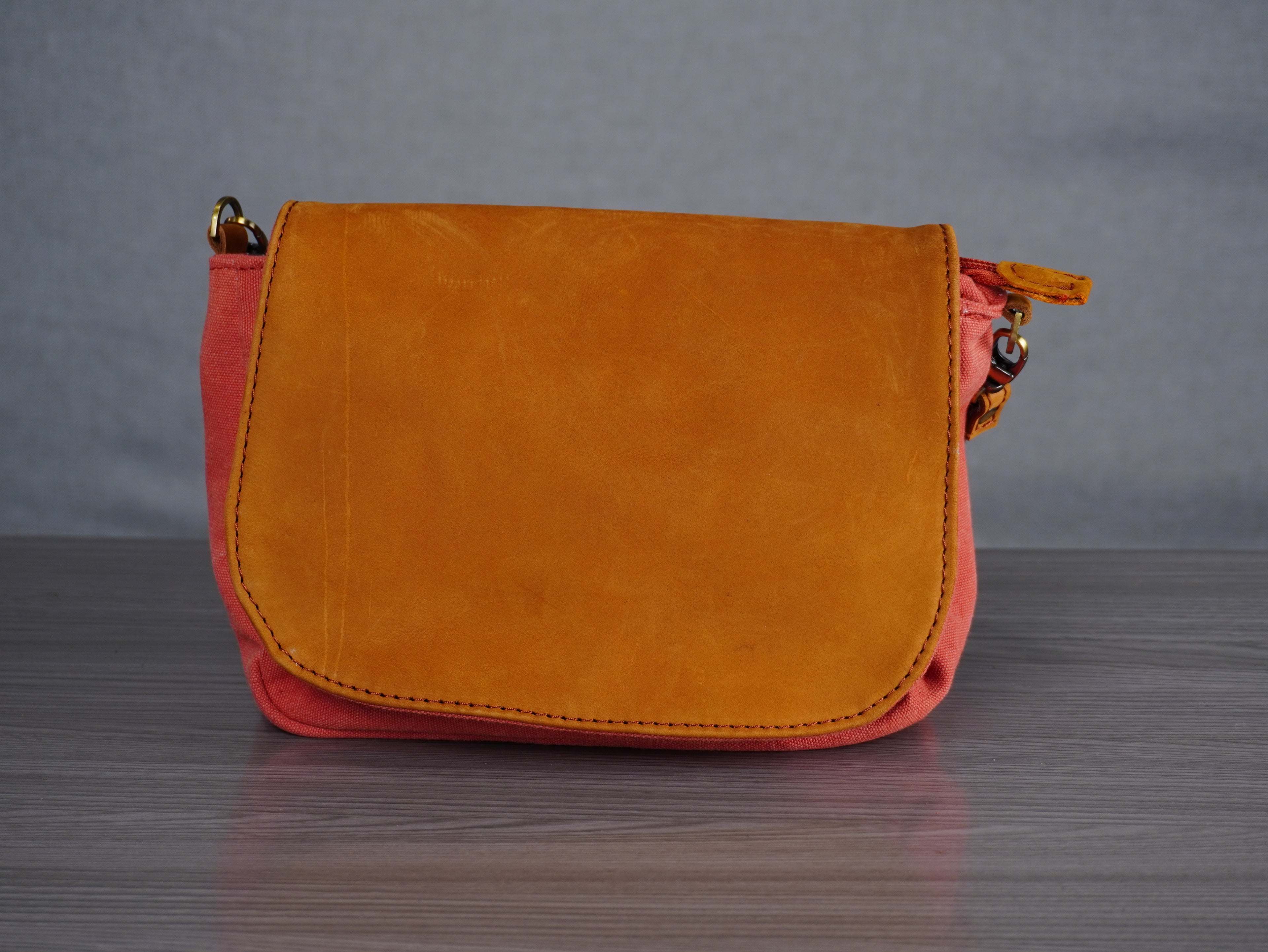 red and leather handbag on a grey surface with a gray background