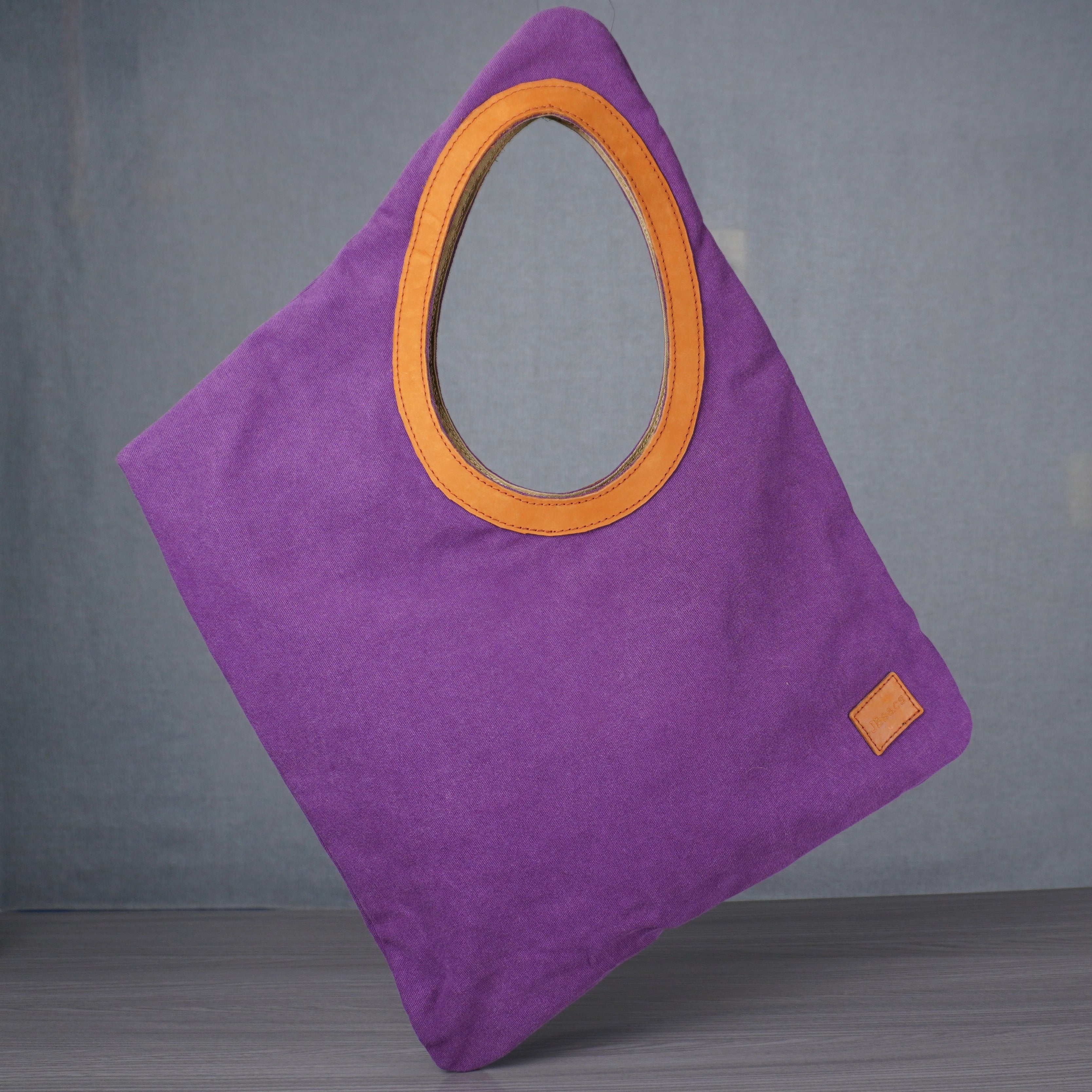 purple bag with yellow leather hole on grey table