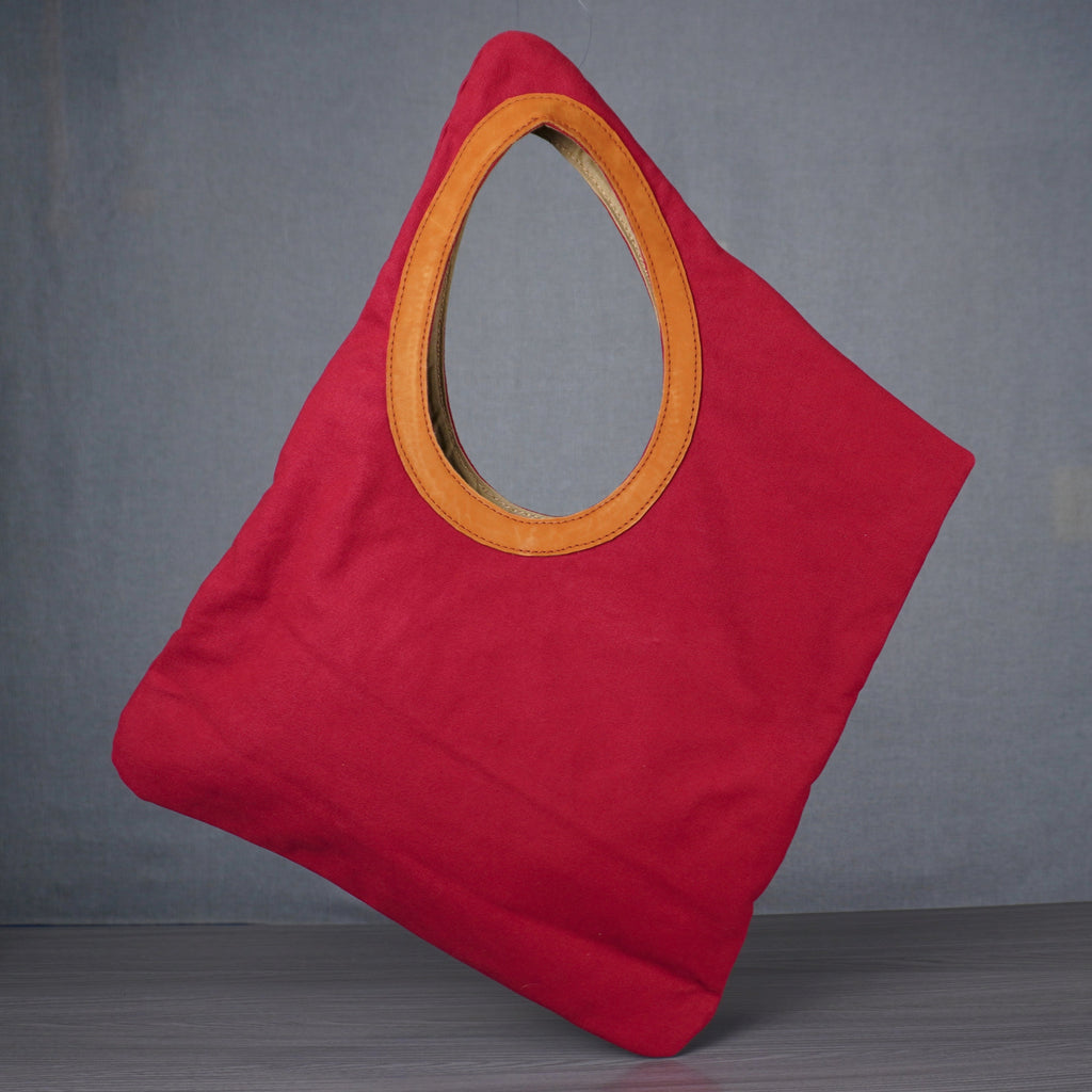 Red bag with a yellow circular handle on a gray floor against a gray wall.