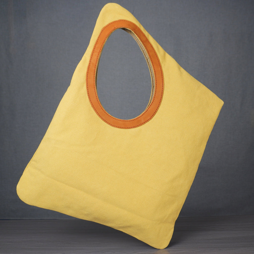 Yellow bag with a circular brown handle on a gray background