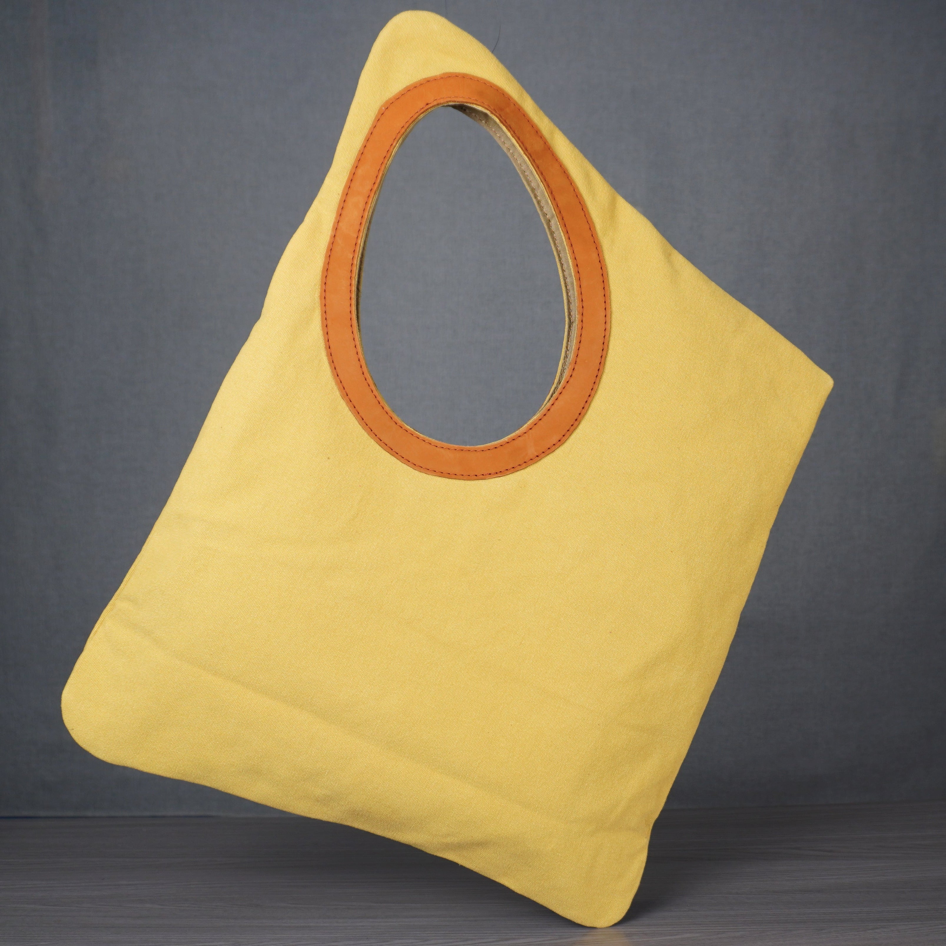 Yellow bag with a circular brown handle on a gray background