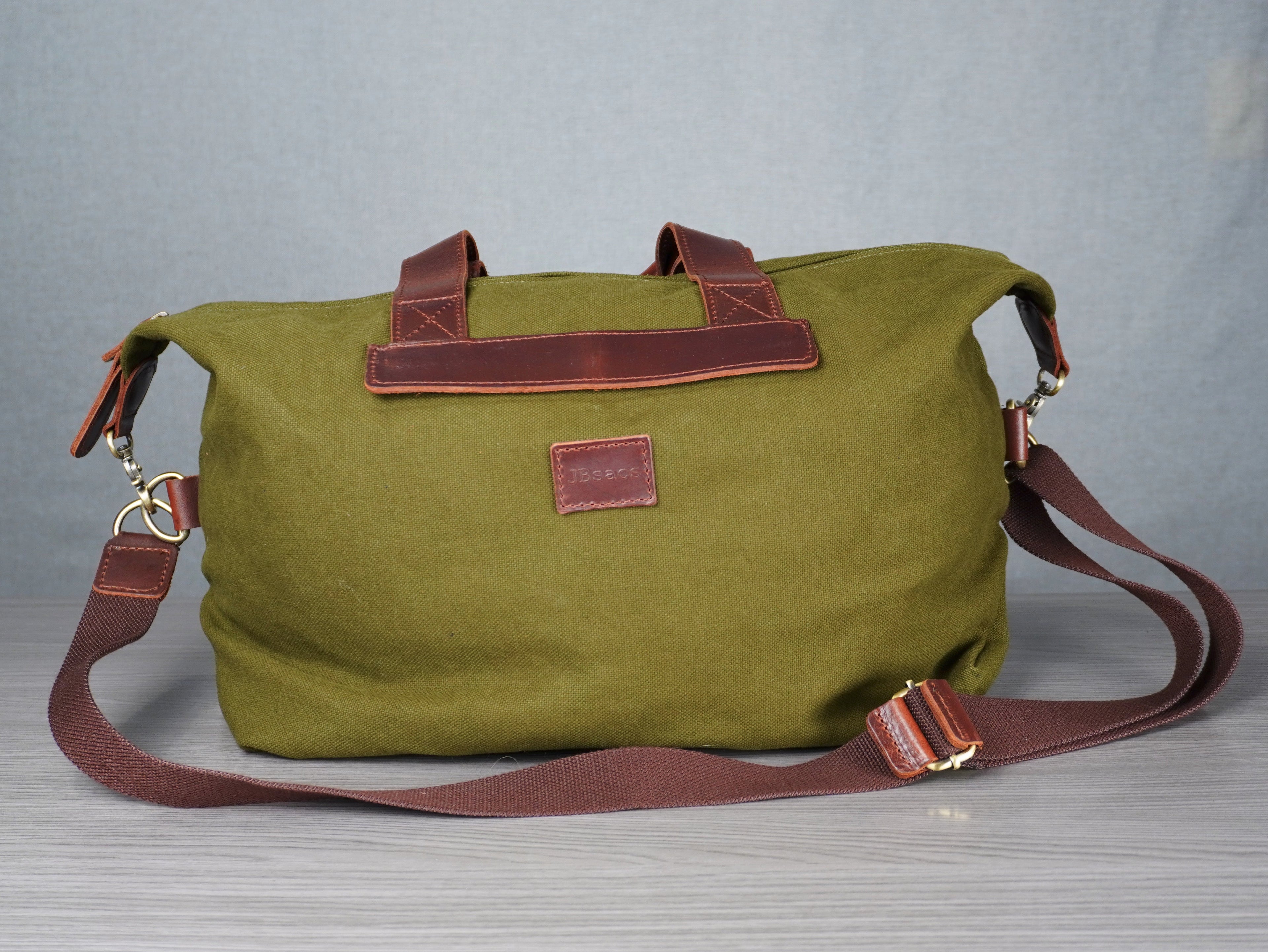 Green bag with leather straps on a gray surface