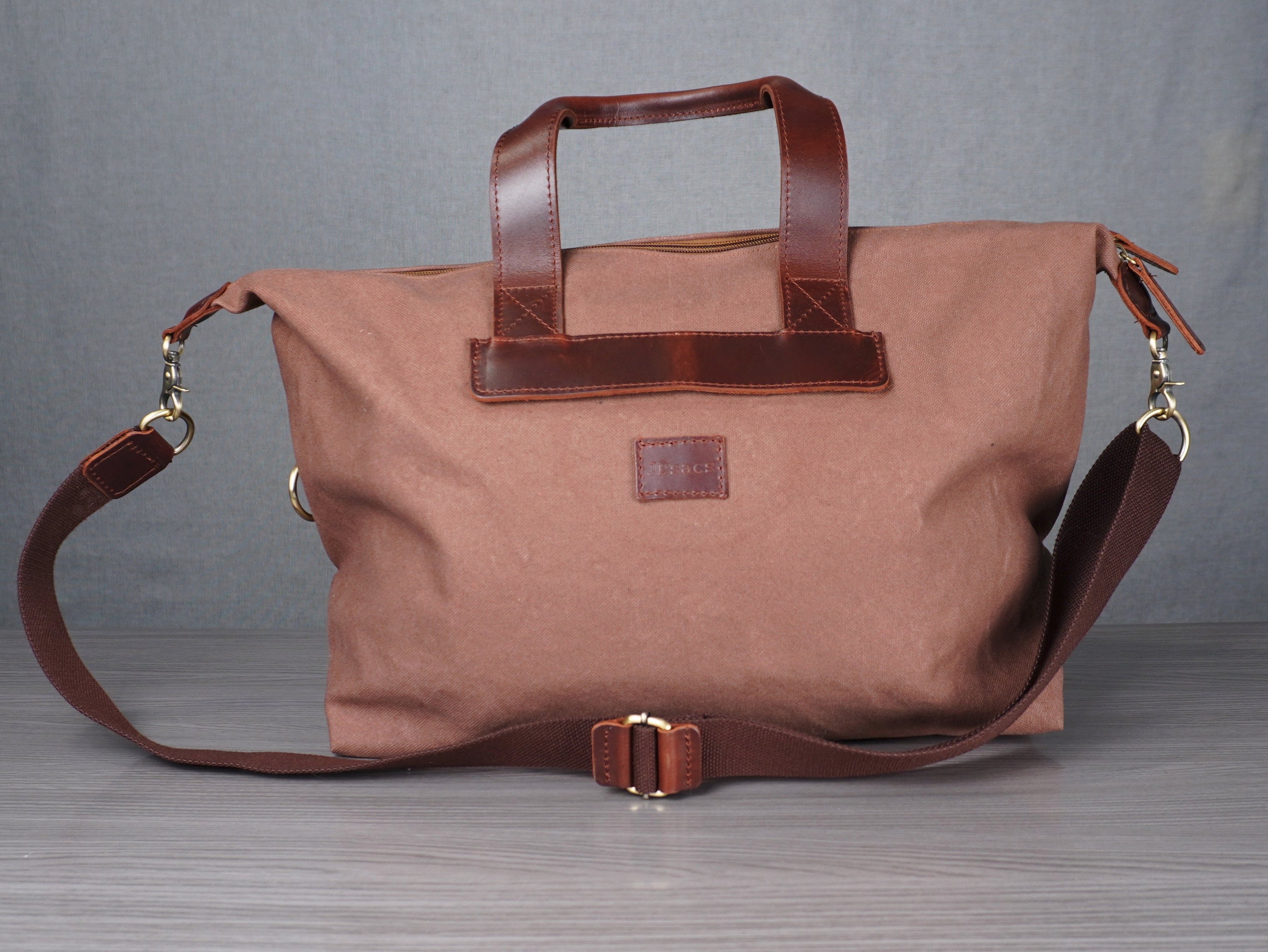 Brown bag with leather straps on a grey surface against a plain background