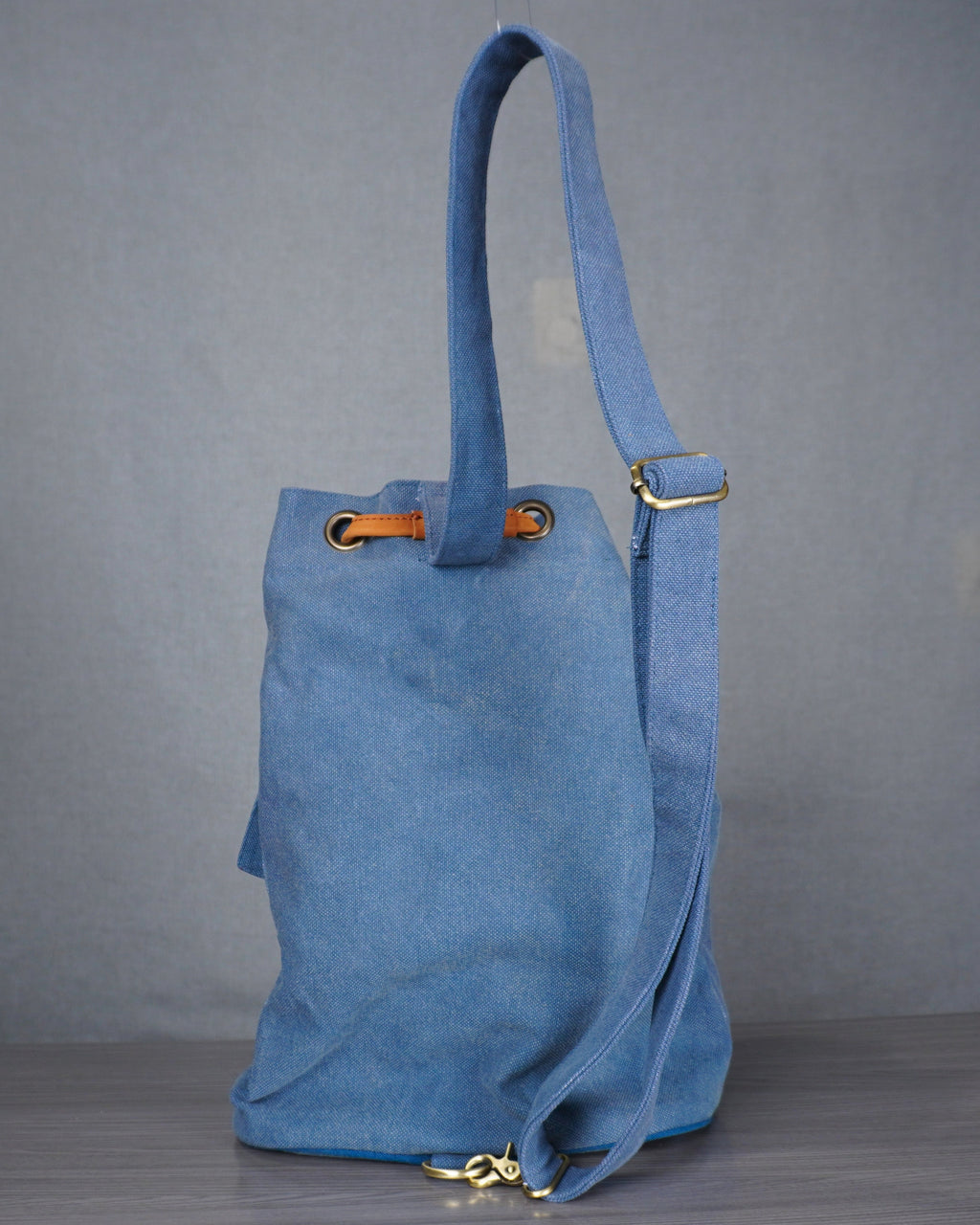 Blue tote bag on a gray floor with a plain background