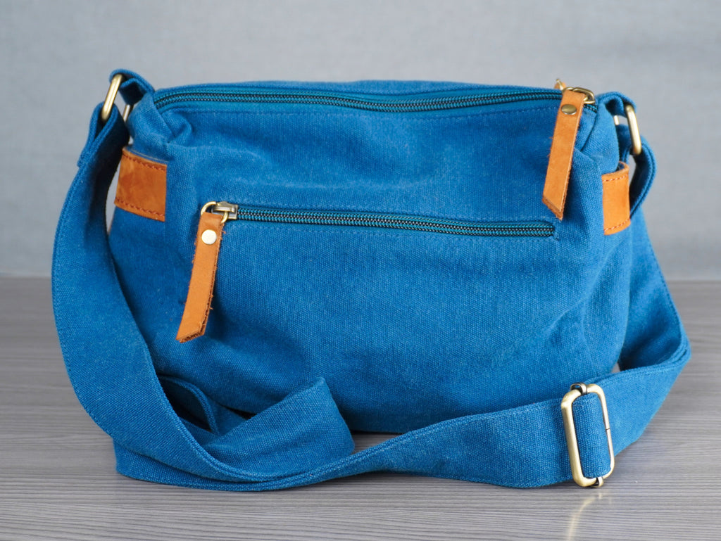 Blue handbag with brown leather accents on a gray surface