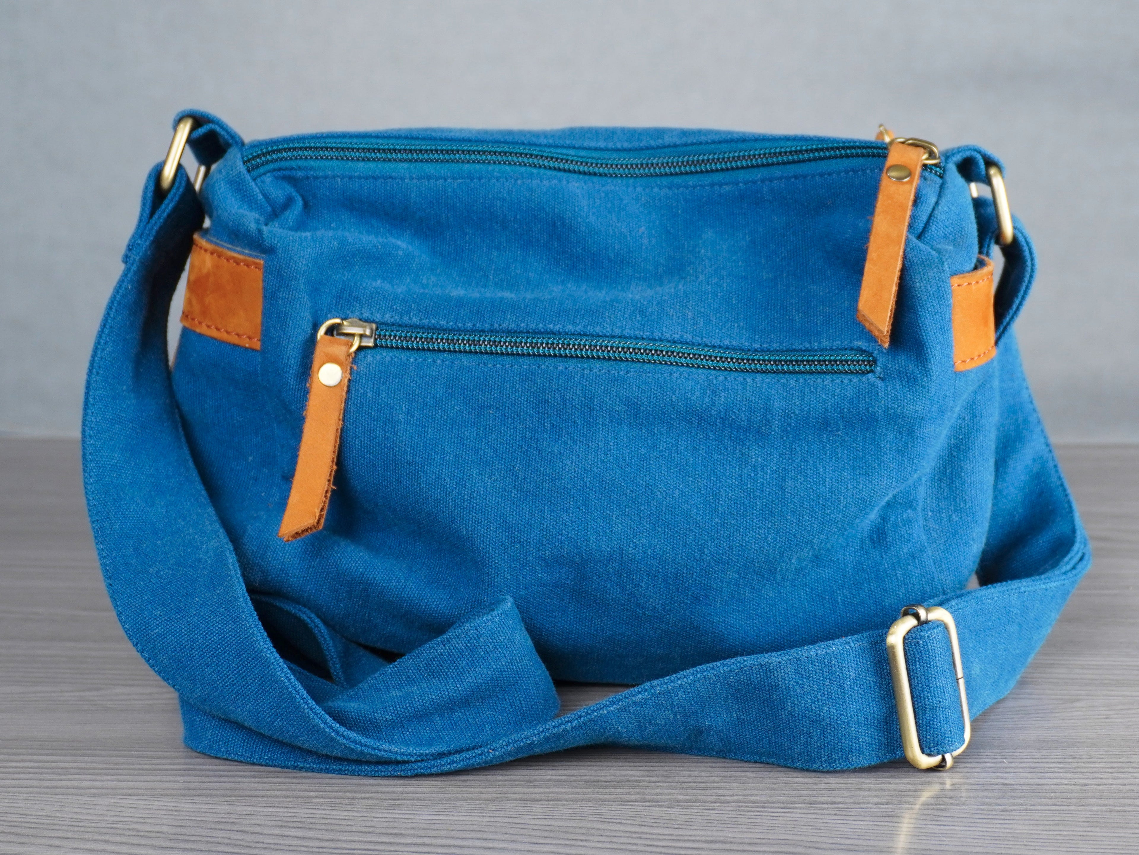 Blue handbag with brown leather accents on a gray surface