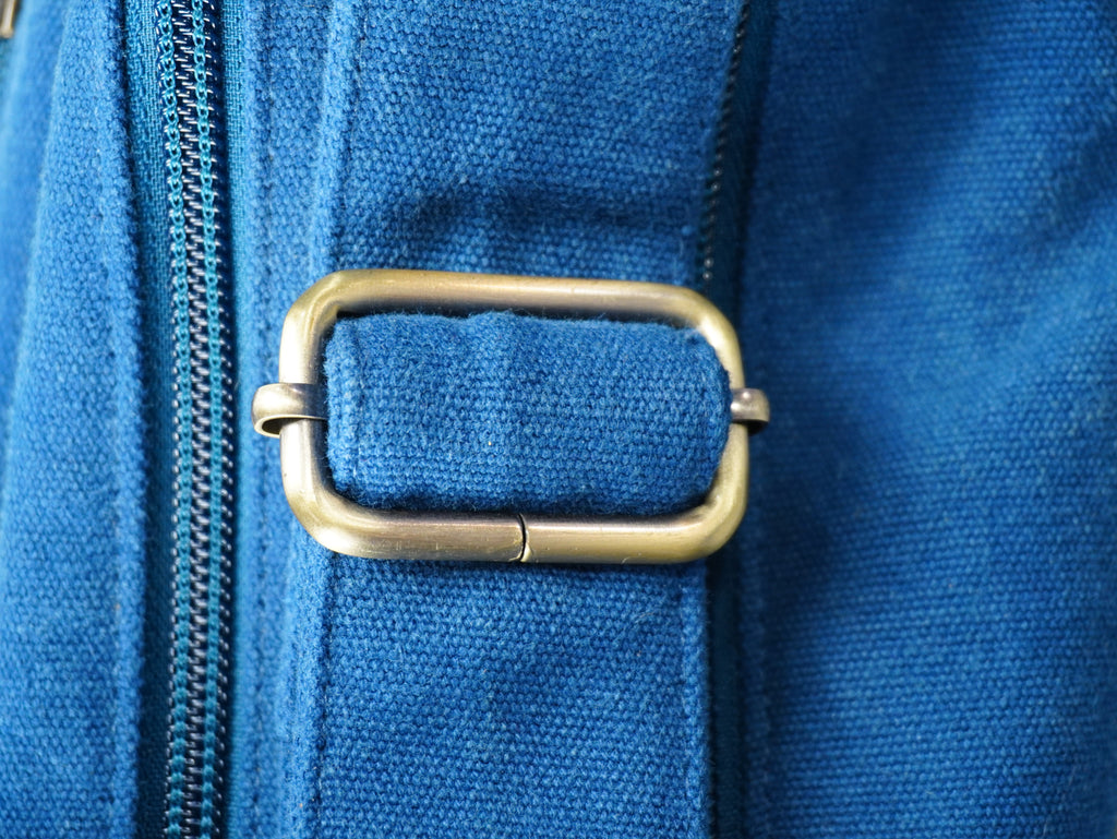 Close-up of a blue bag with a brass buckle