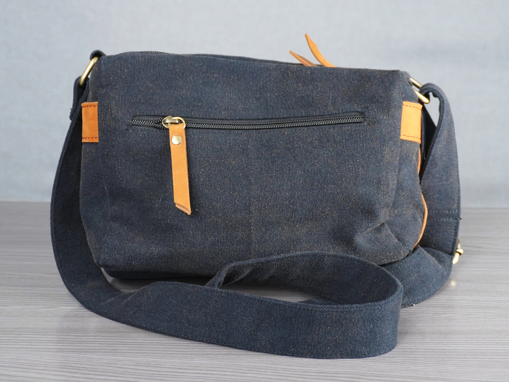 black messenger bag with yellow accents on a gray surface