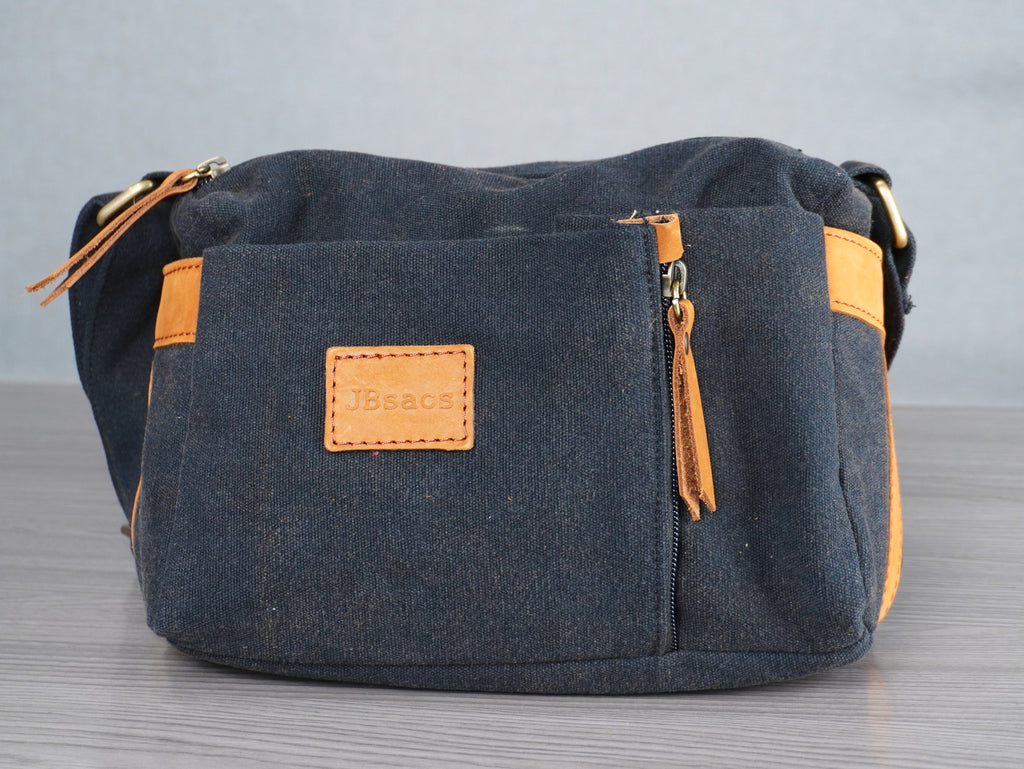 black shoulder bag with yellow leather accents on a gray surface