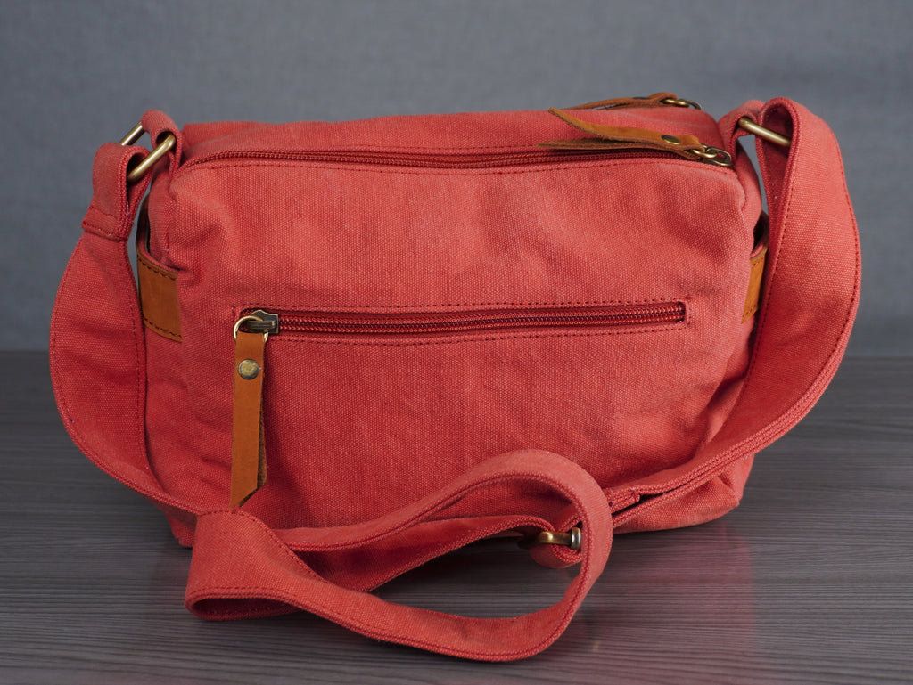Red shoulder bag on a wooden surface with a gray background