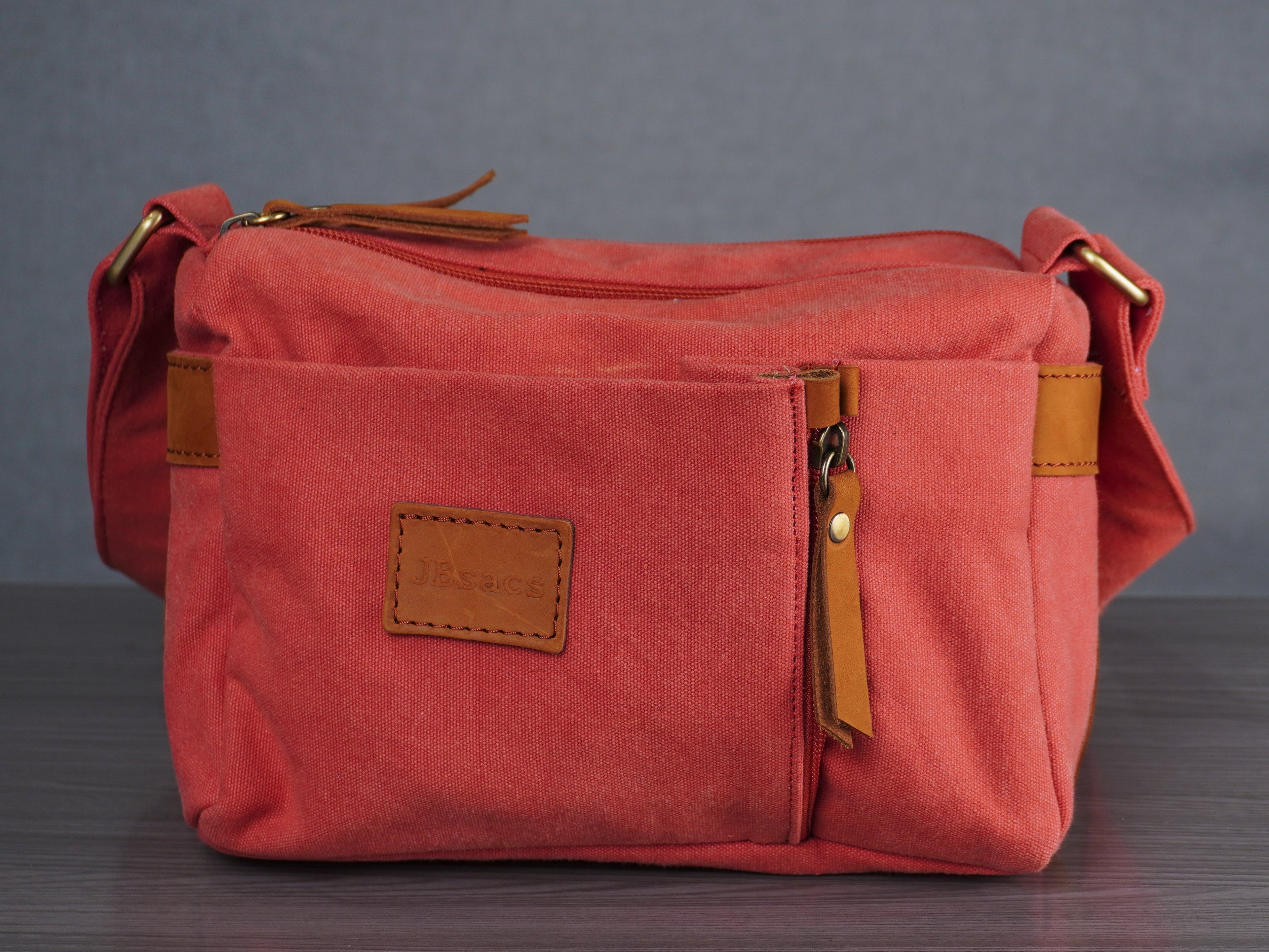Red bag with brown leather accents on a wooden surface and gray background
