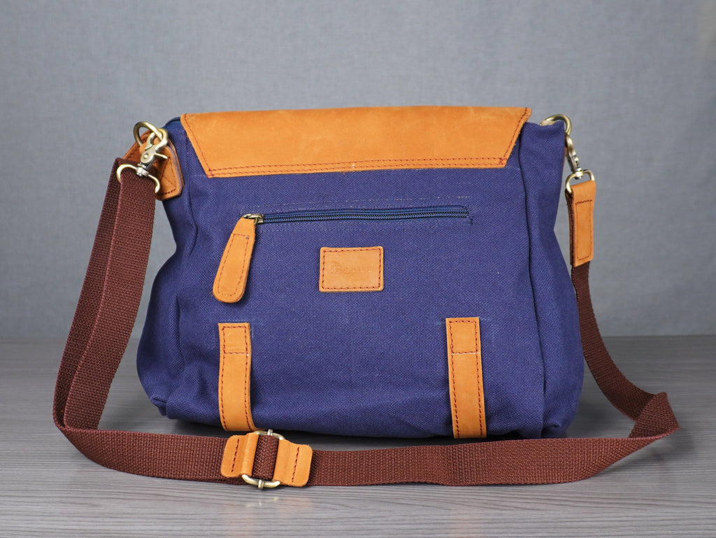 Purple and orange handbag on a metal table with a gray curtain background