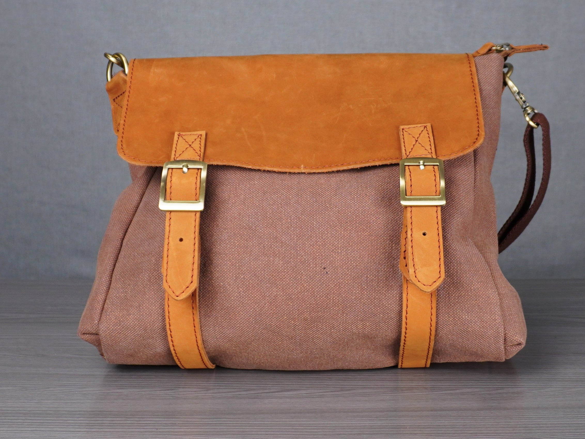 Brown and orange handbag on a gray surface with a plain background