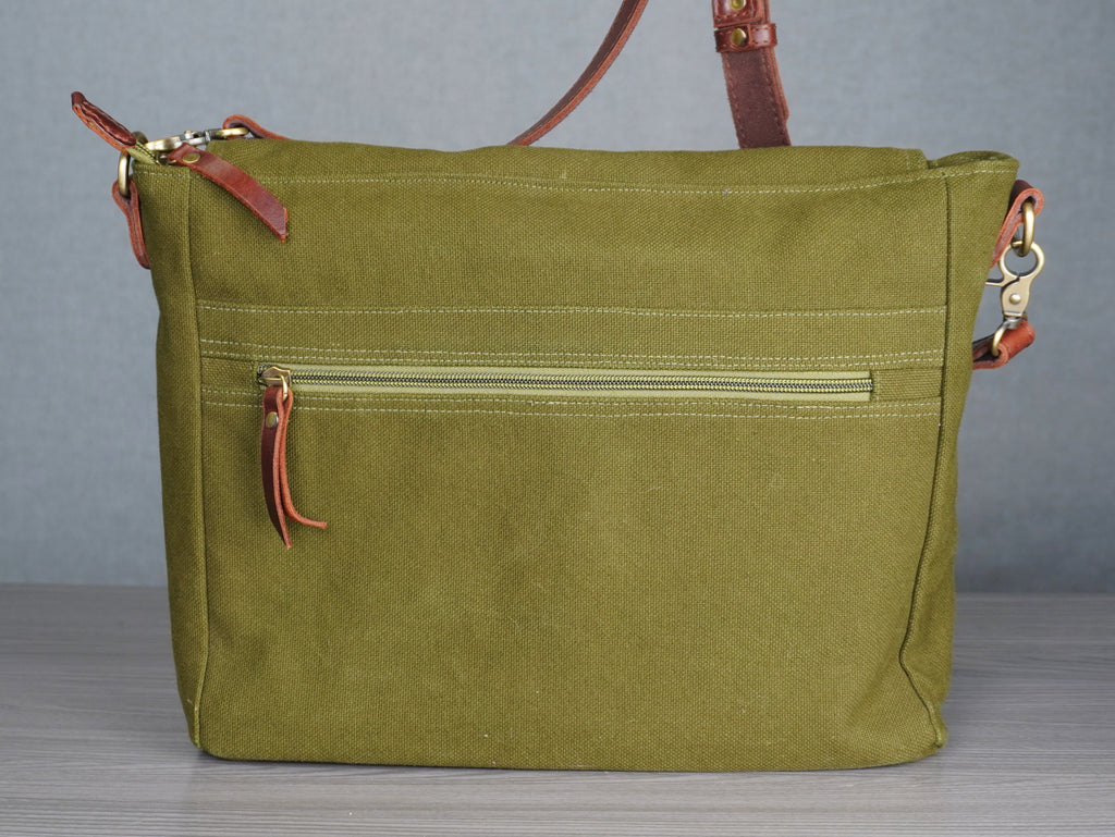 Green handbag with brown leather straps on a gray background