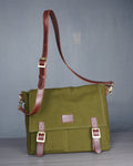 Green bag with brown leather strap on a gray background
