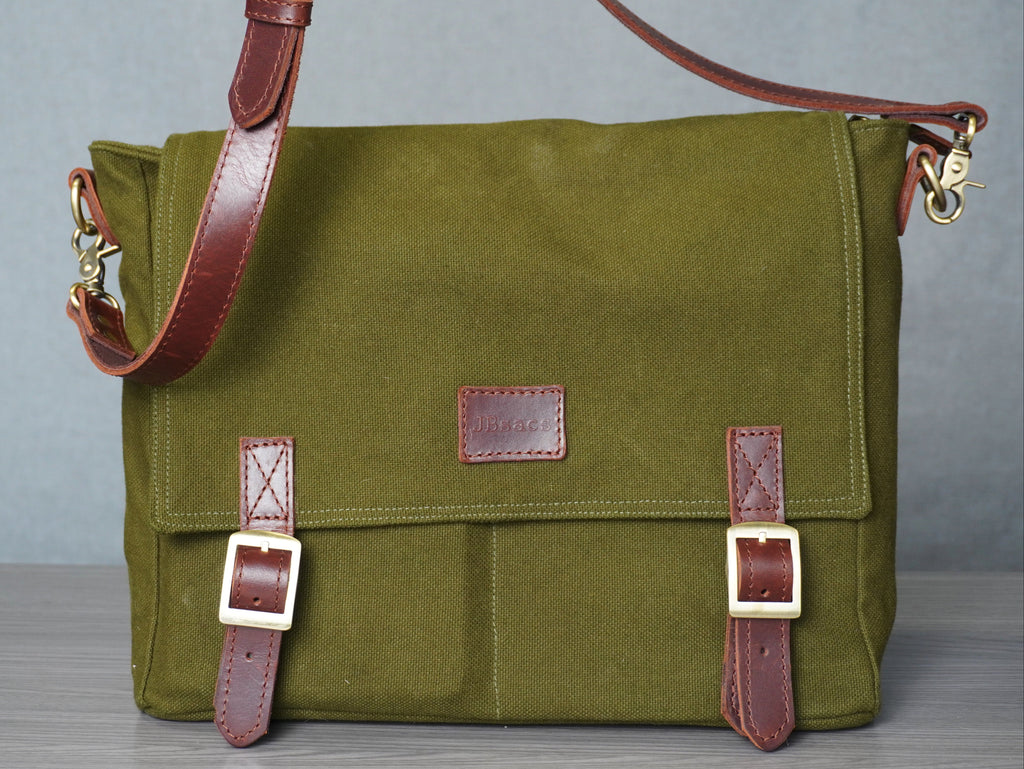 Green canvas bag with brown leather straps on a gray background