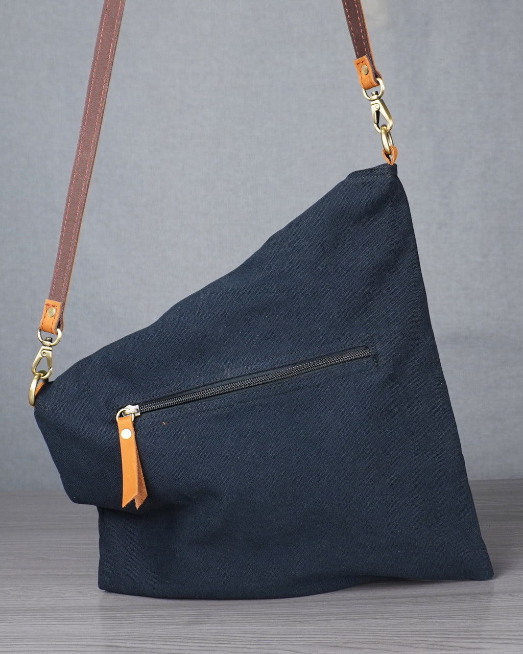 black bag with gold zippers on a gray surface against a plain background