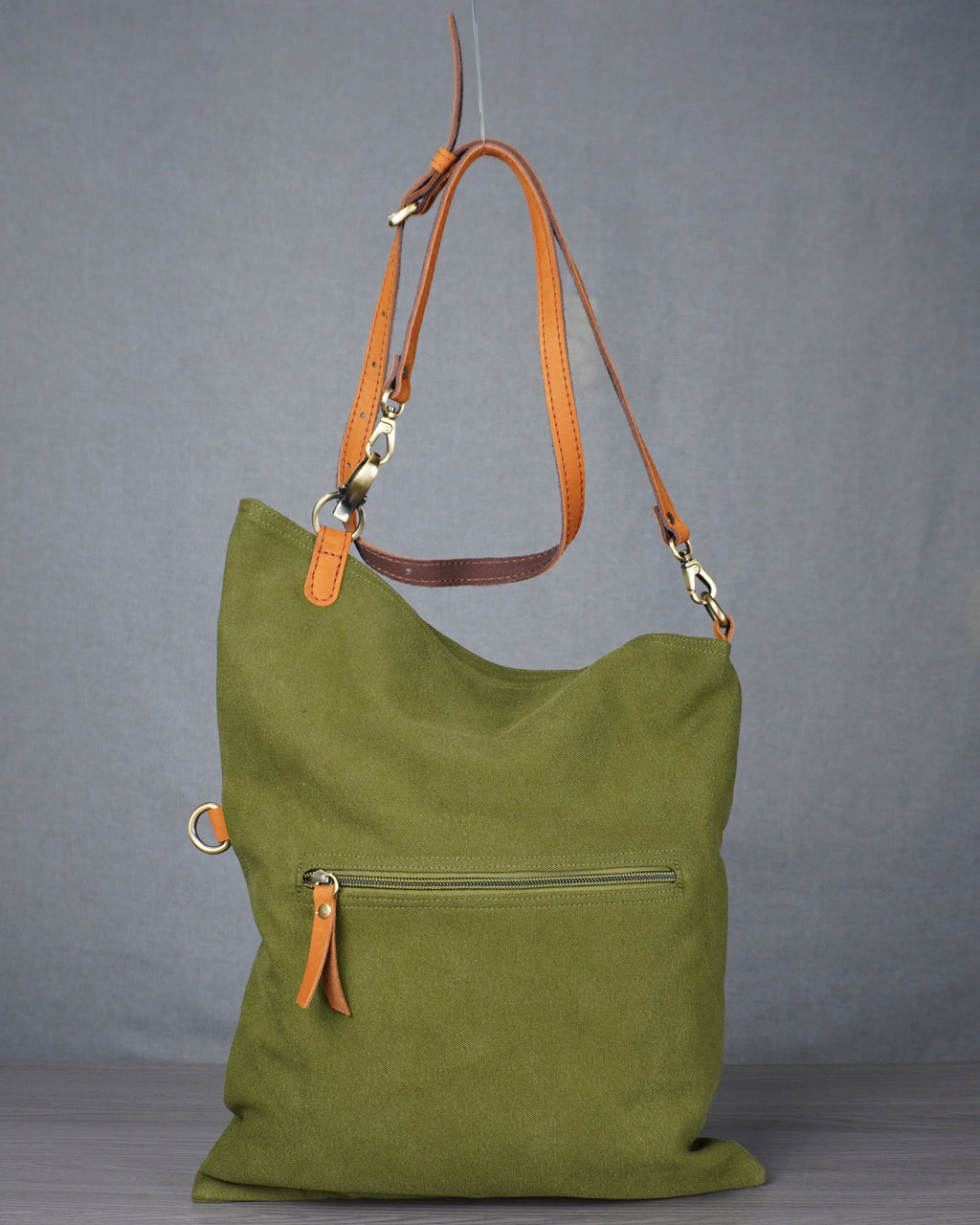 Green handbag with orange accents hanging against a gray background