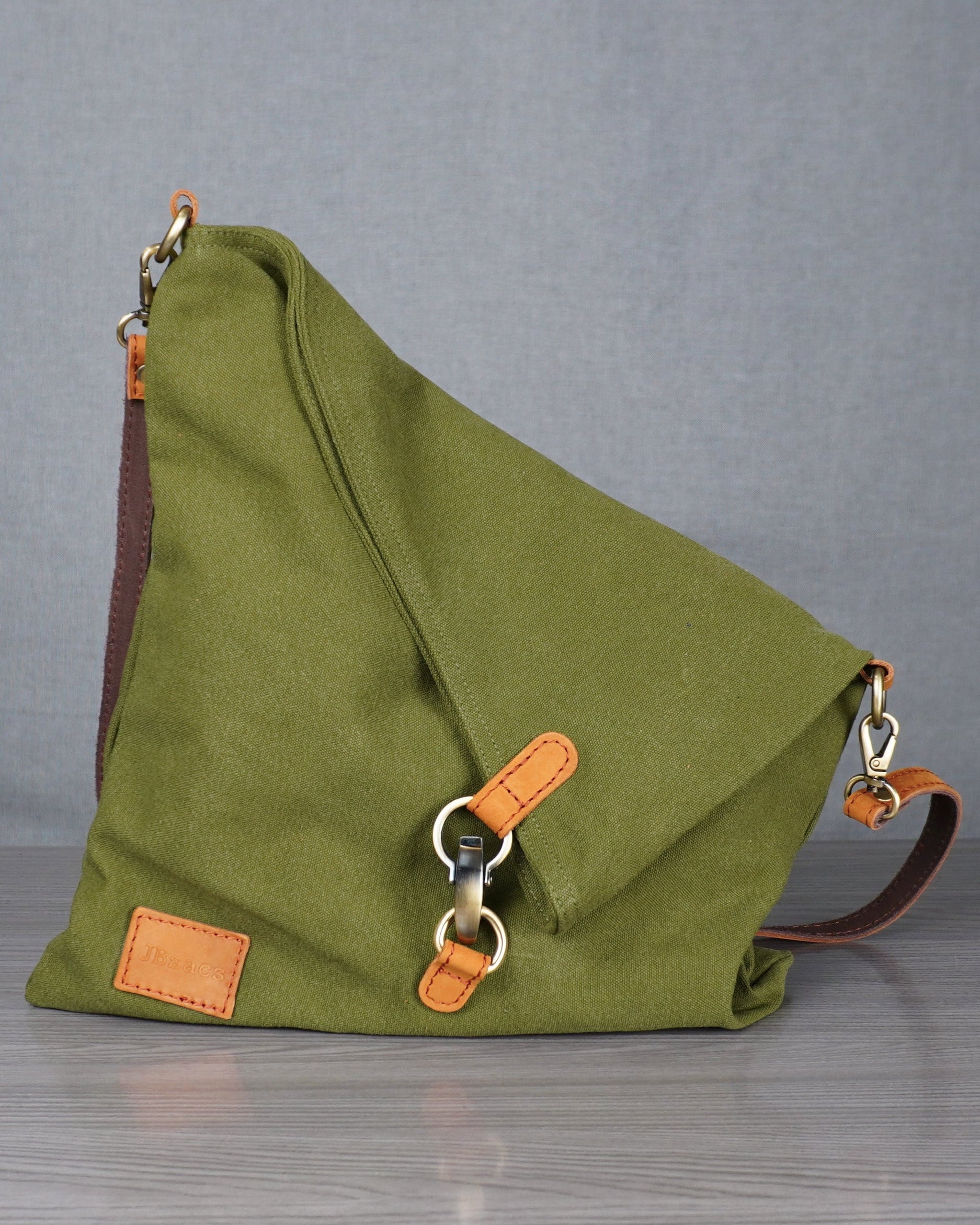 Green bag with orange accents on a metal table against a plain background