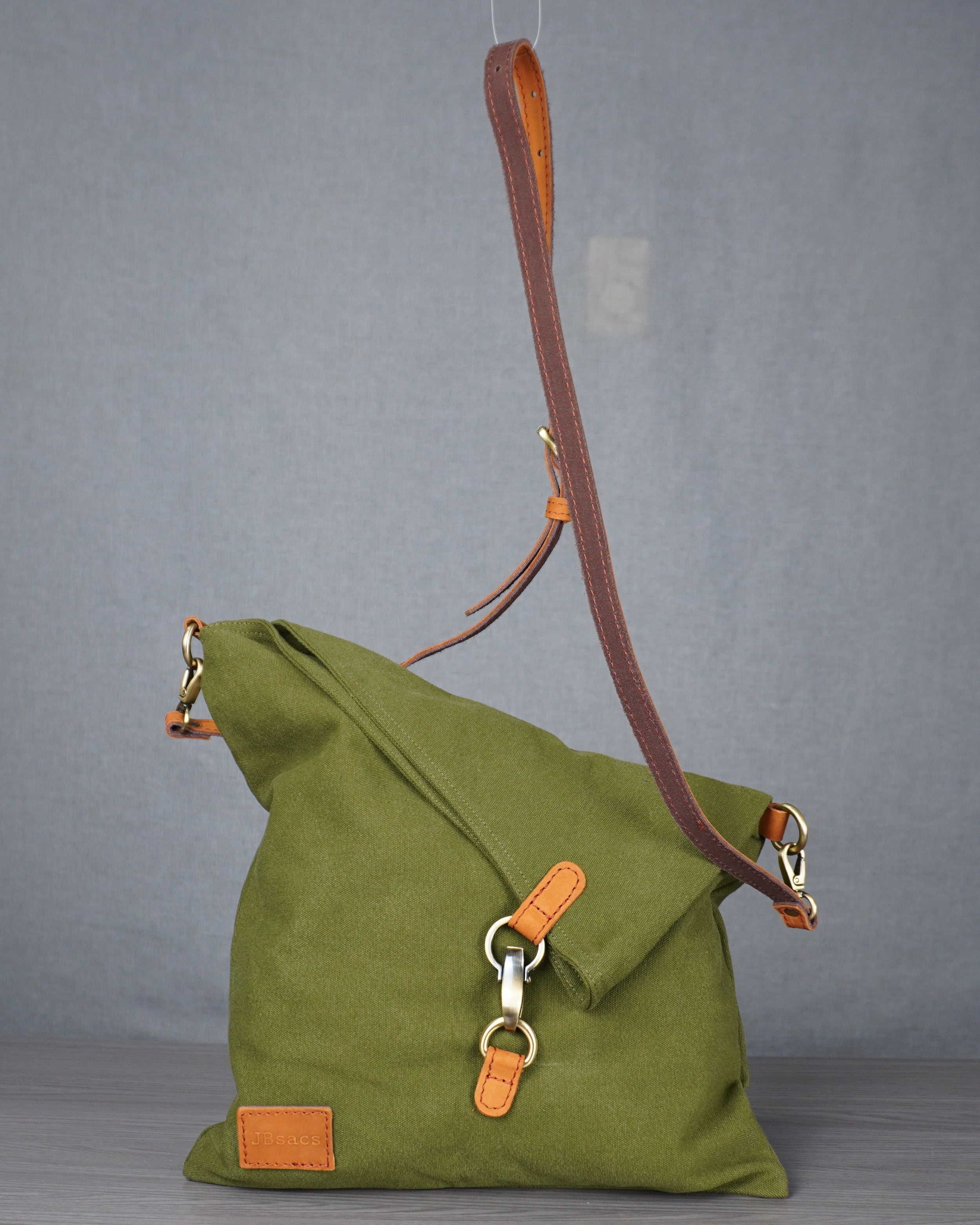 Green handbag with orange accents on a gray surface against a plain background