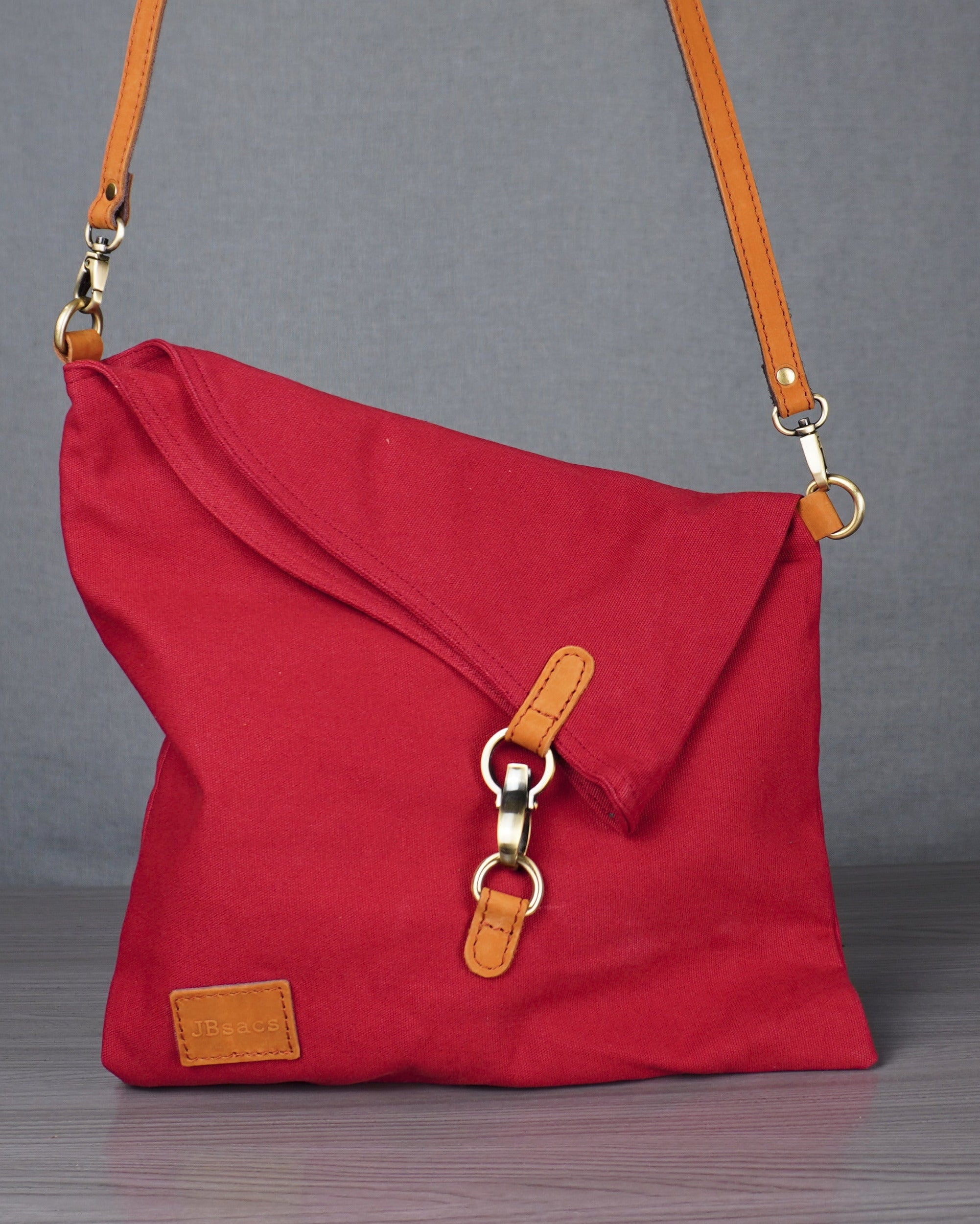 Red shoulder bag with orange strap on a gray surface