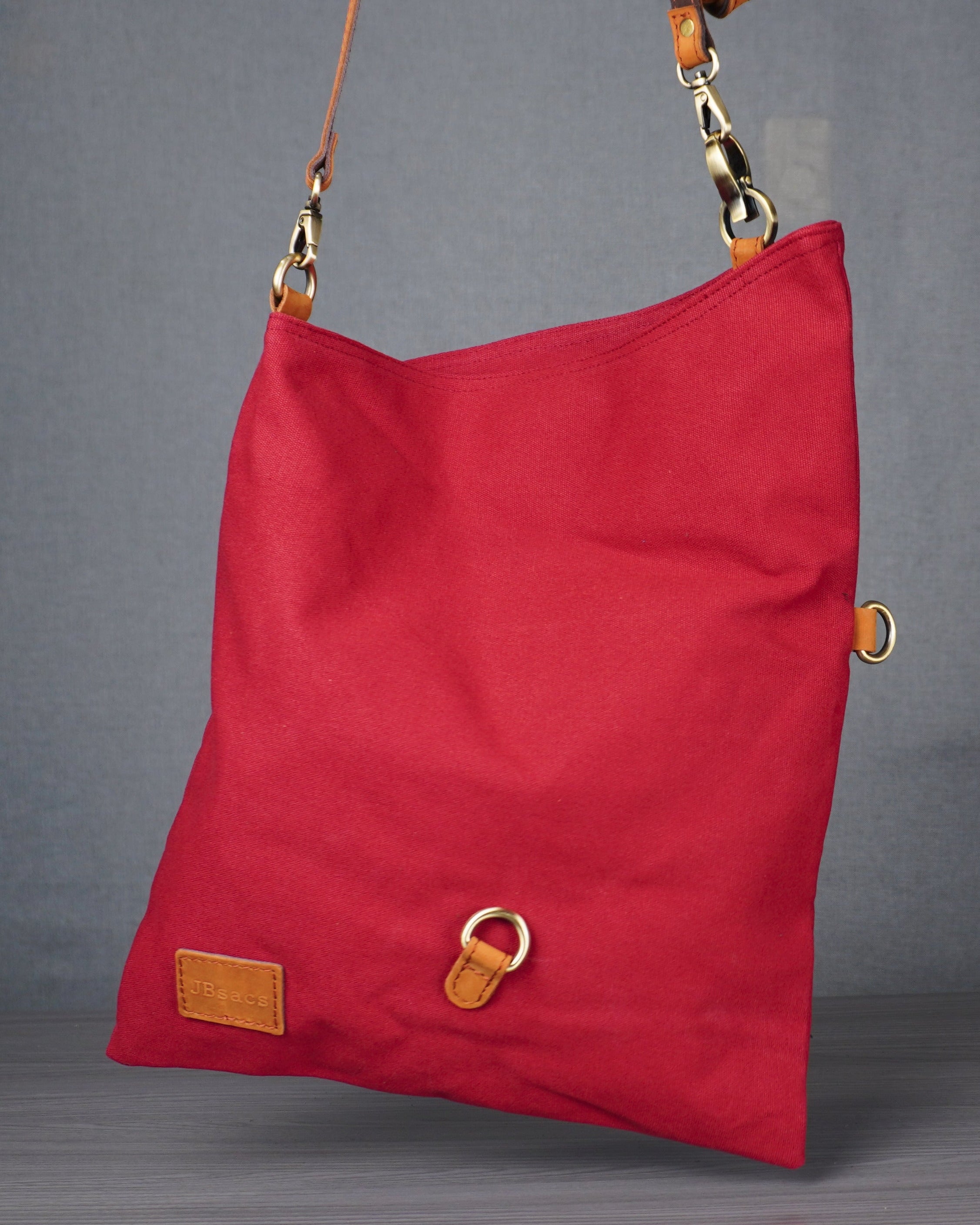 Red bag with gold accents hanging on a stand against a gray background