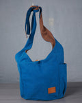 Blue shoulder bag with brown accents on a gray background