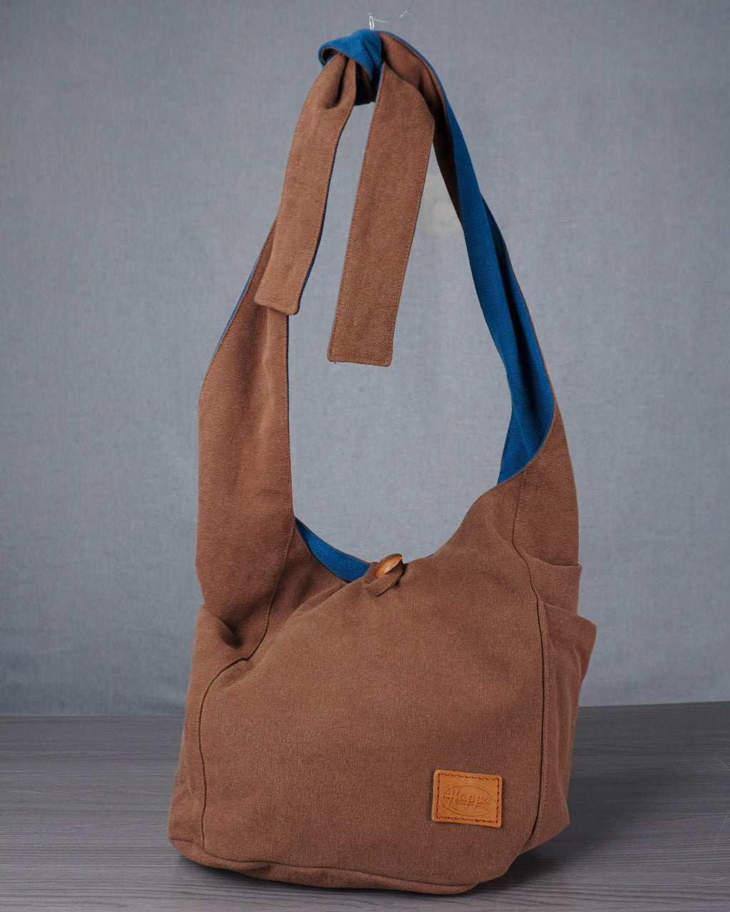 Brown shoulder bag with blue interior on a gray background