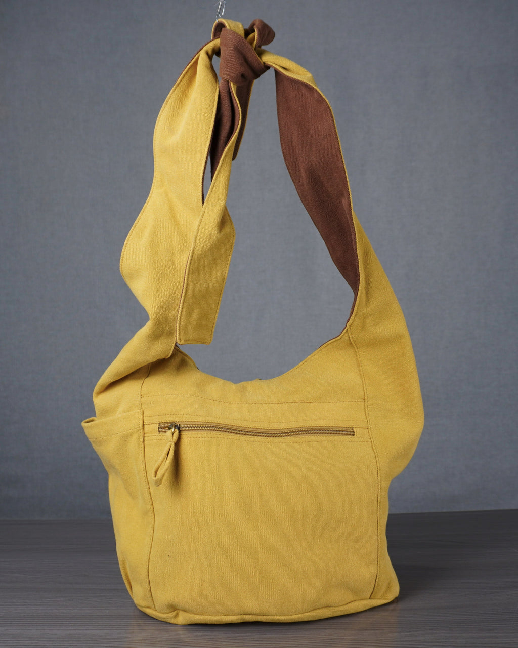 Yellow bag hanging against a gray backdrop with a blue wall and door in the background.