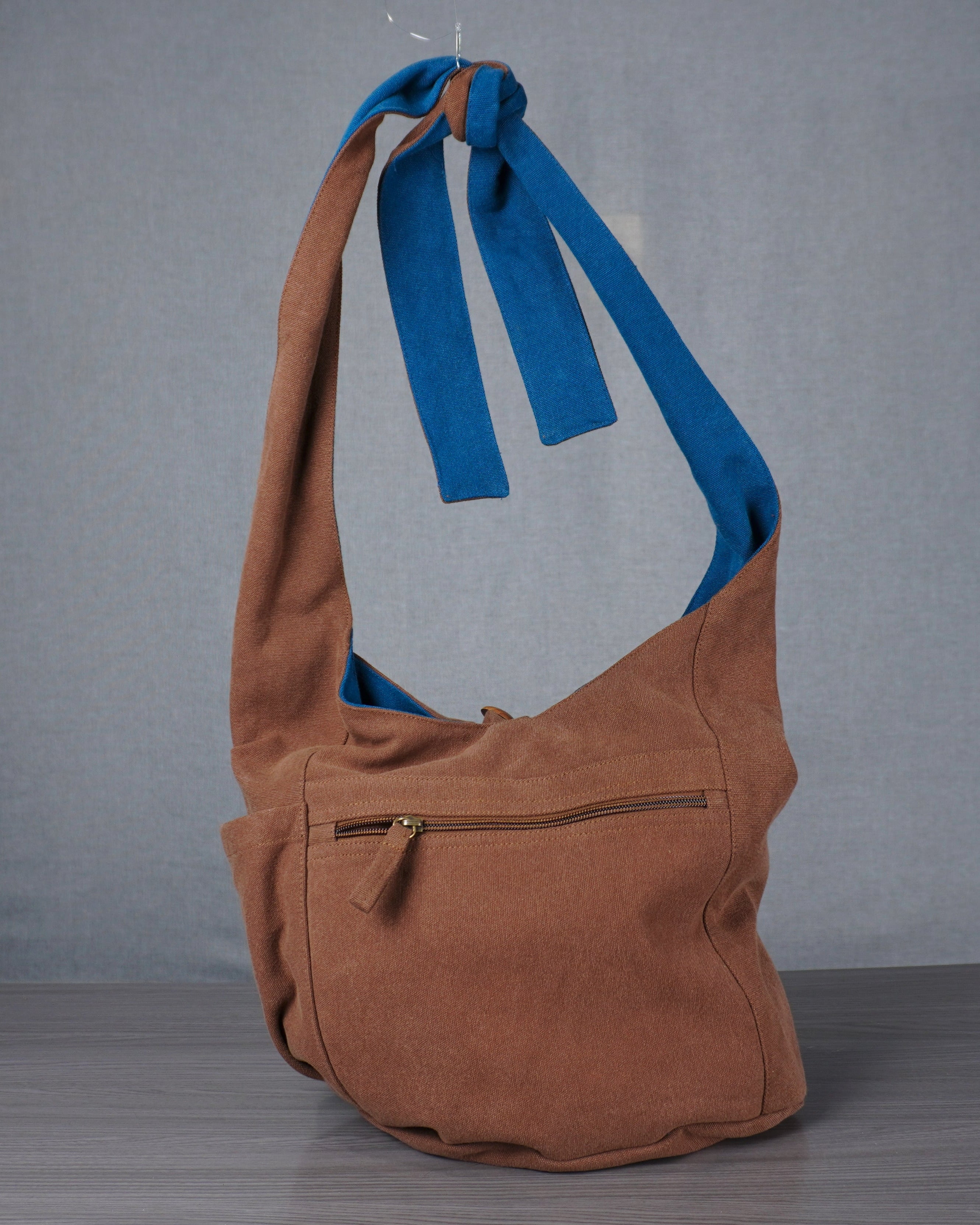 Brown bag with blue straps on a gray background