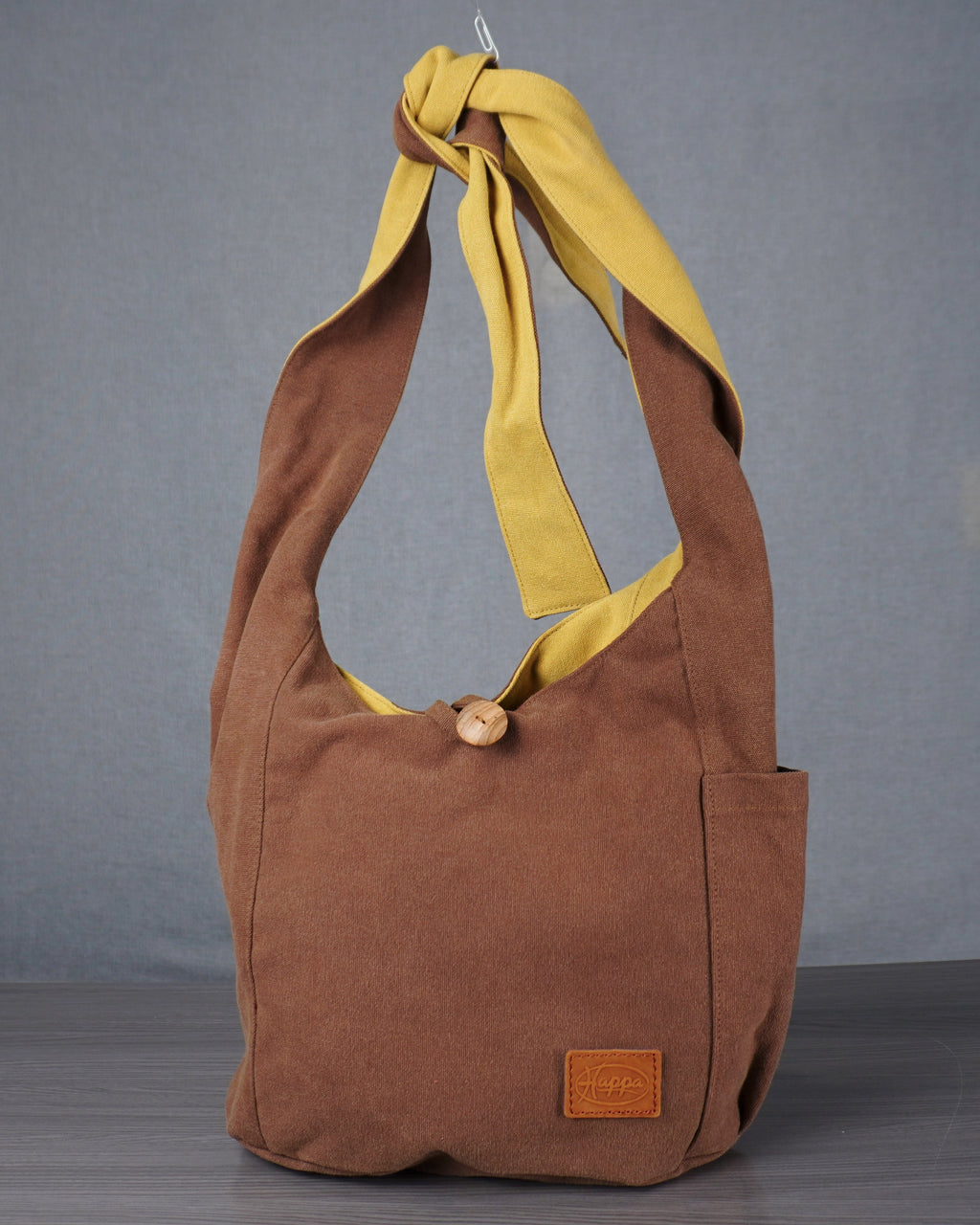 Brown shoulder bag with yellow strap on a gray background