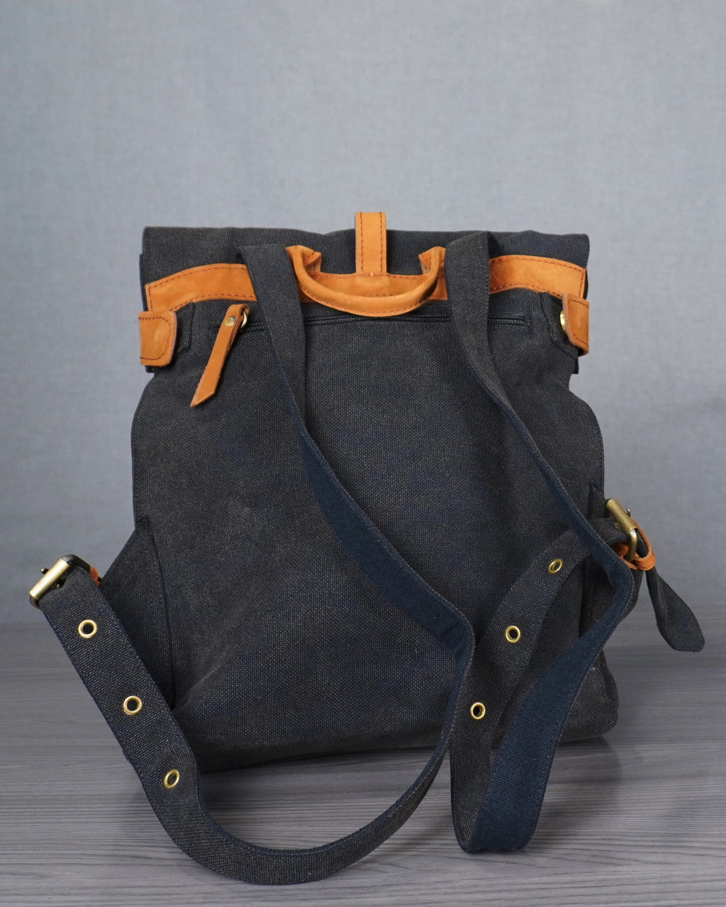 Gray backpack with orange accents on a gray floor against a plain backdrop