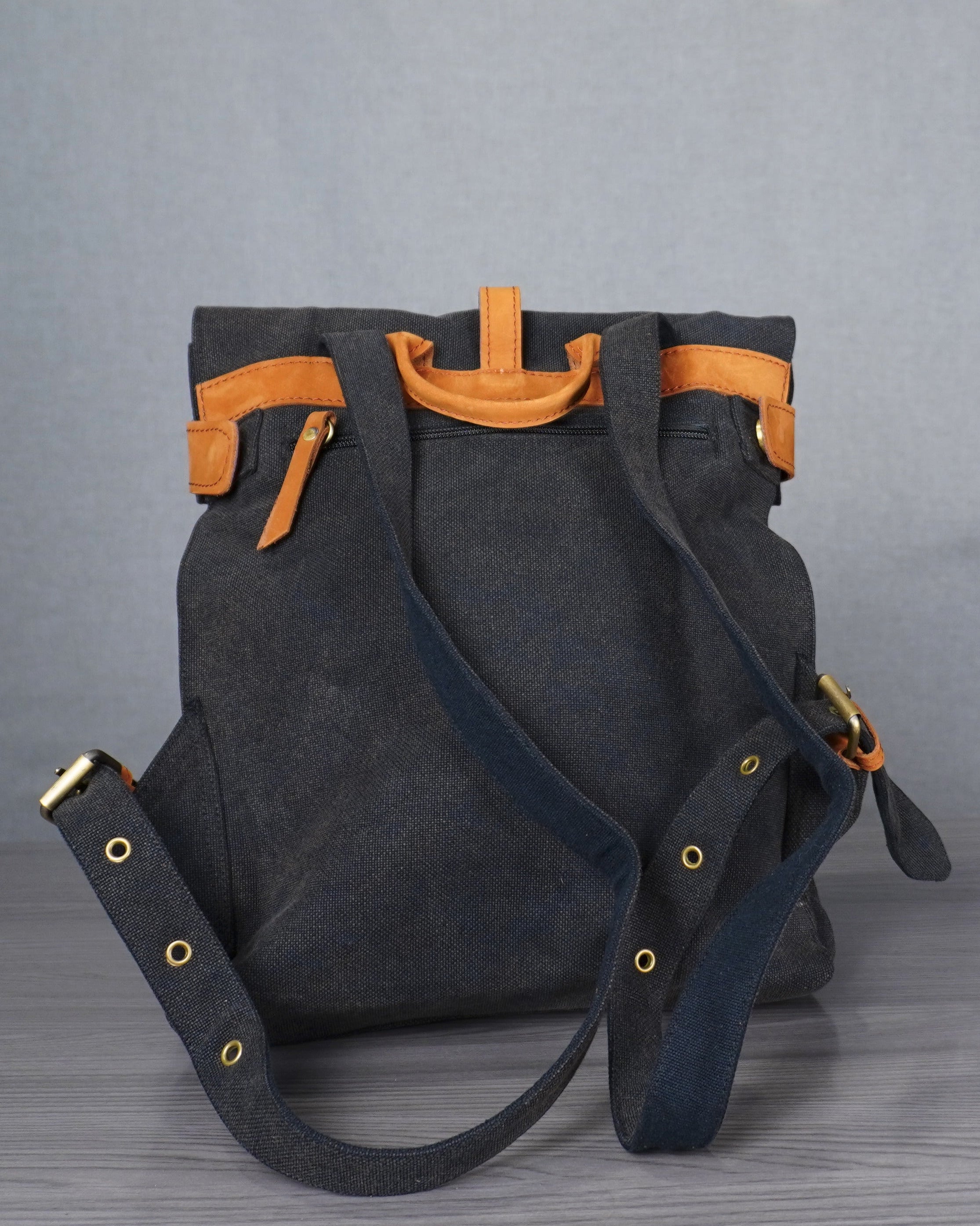 Gray backpack with orange accents on a gray floor against a plain backdrop