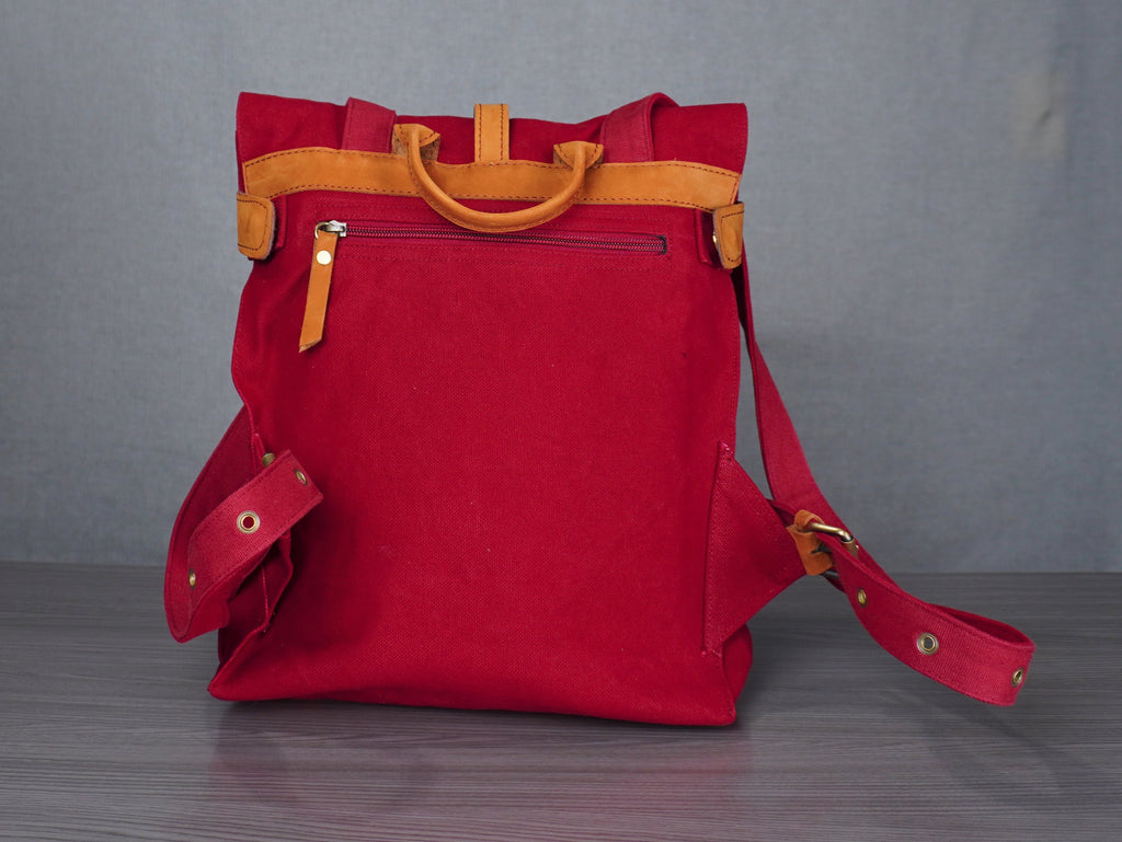 Red bag with yellow handles on a gray surface against a plain background
