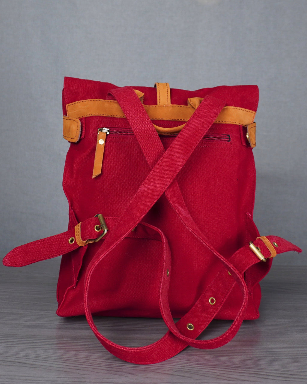 Red backpack with yellow accents on a gray floor against a blue wall.