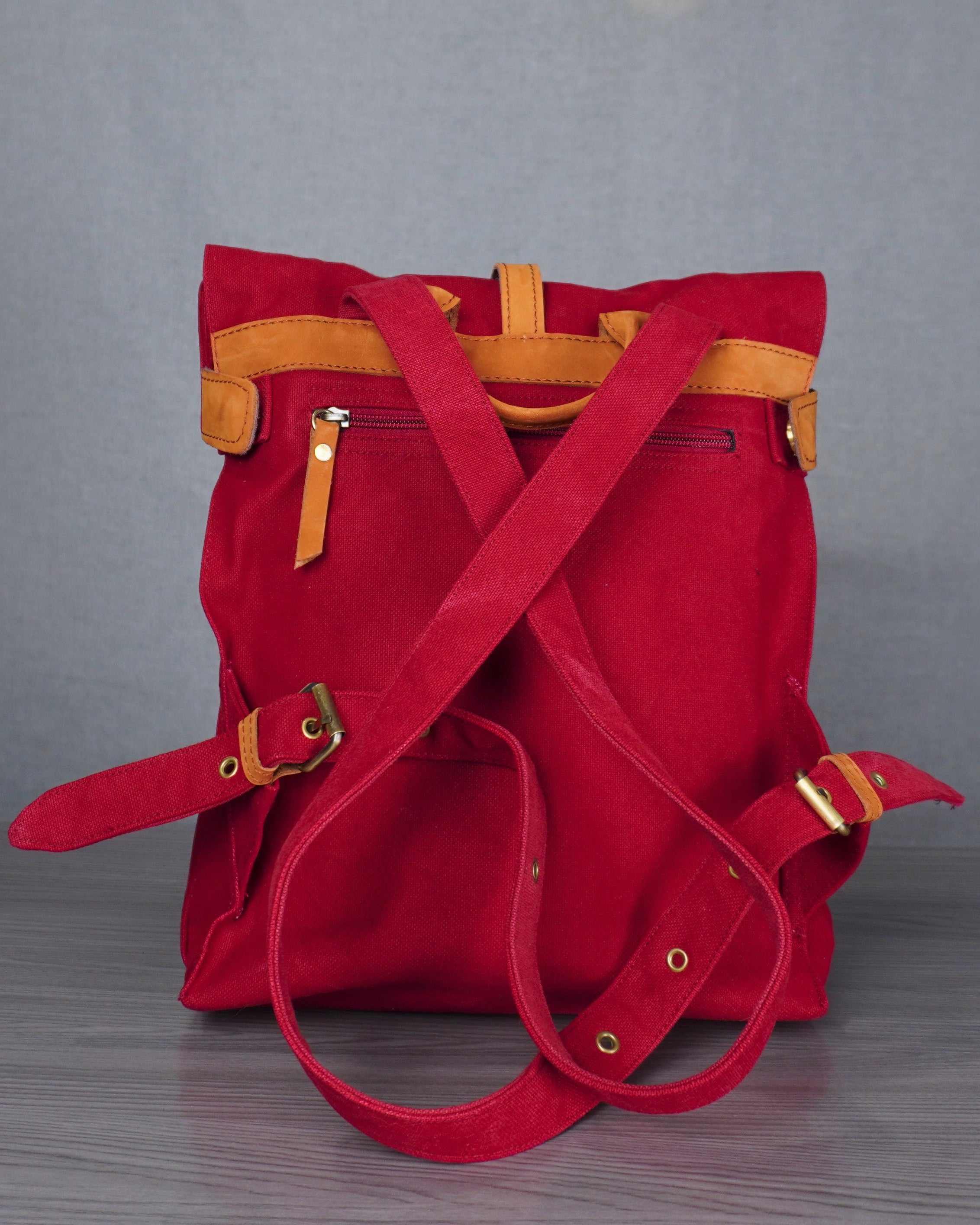 Red backpack with yellow accents on a gray floor against a blue wall.