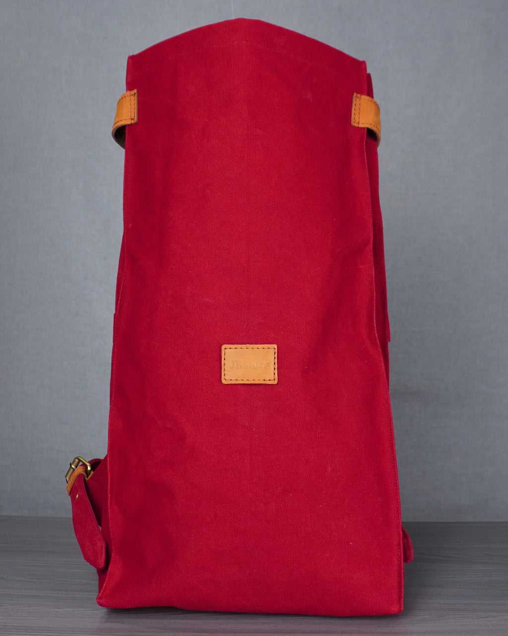 Red backpack with yellow accents on a gray floor against a blue wall.