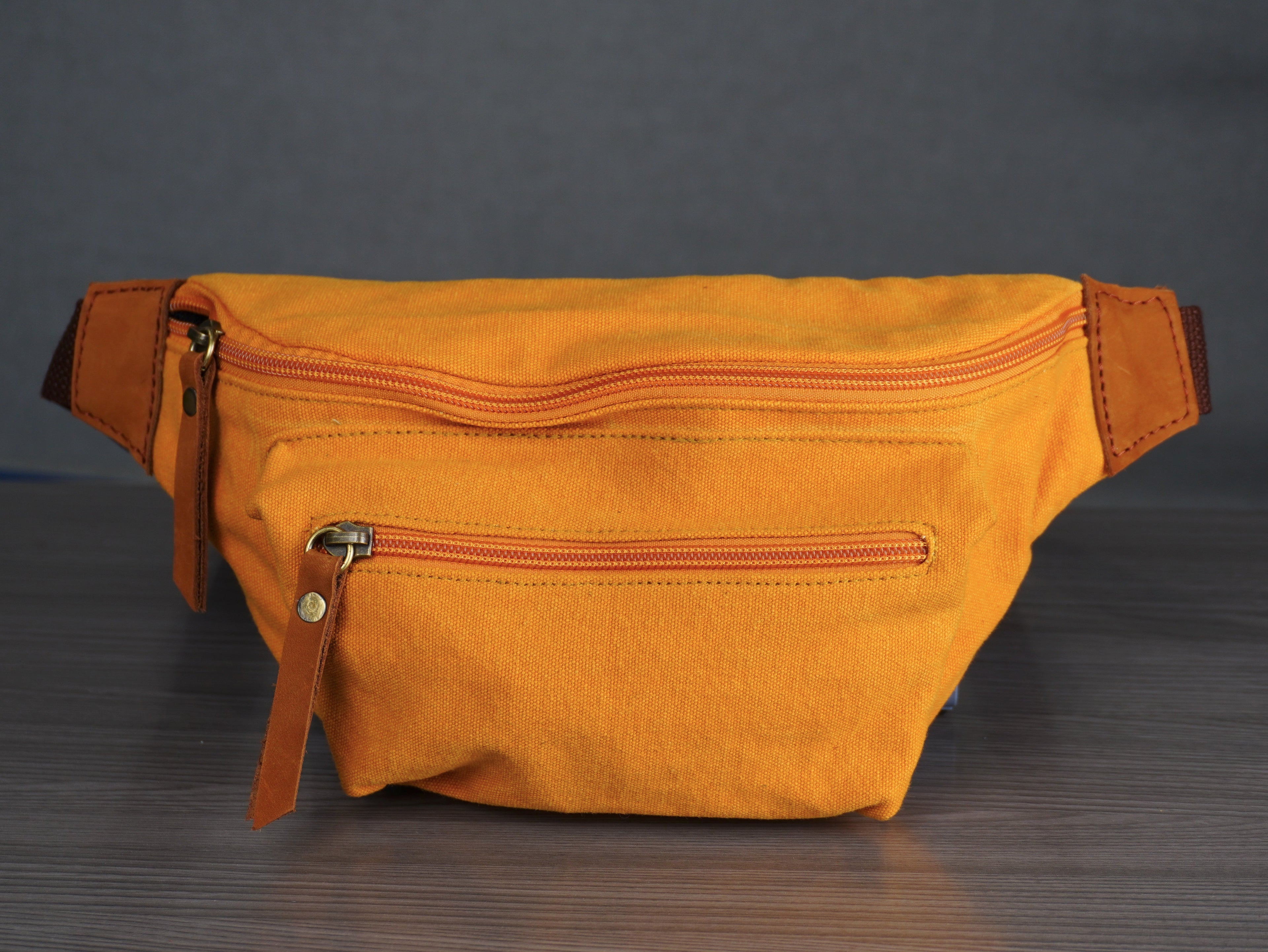 Yellow waist bag on a dark surface with a gray background
