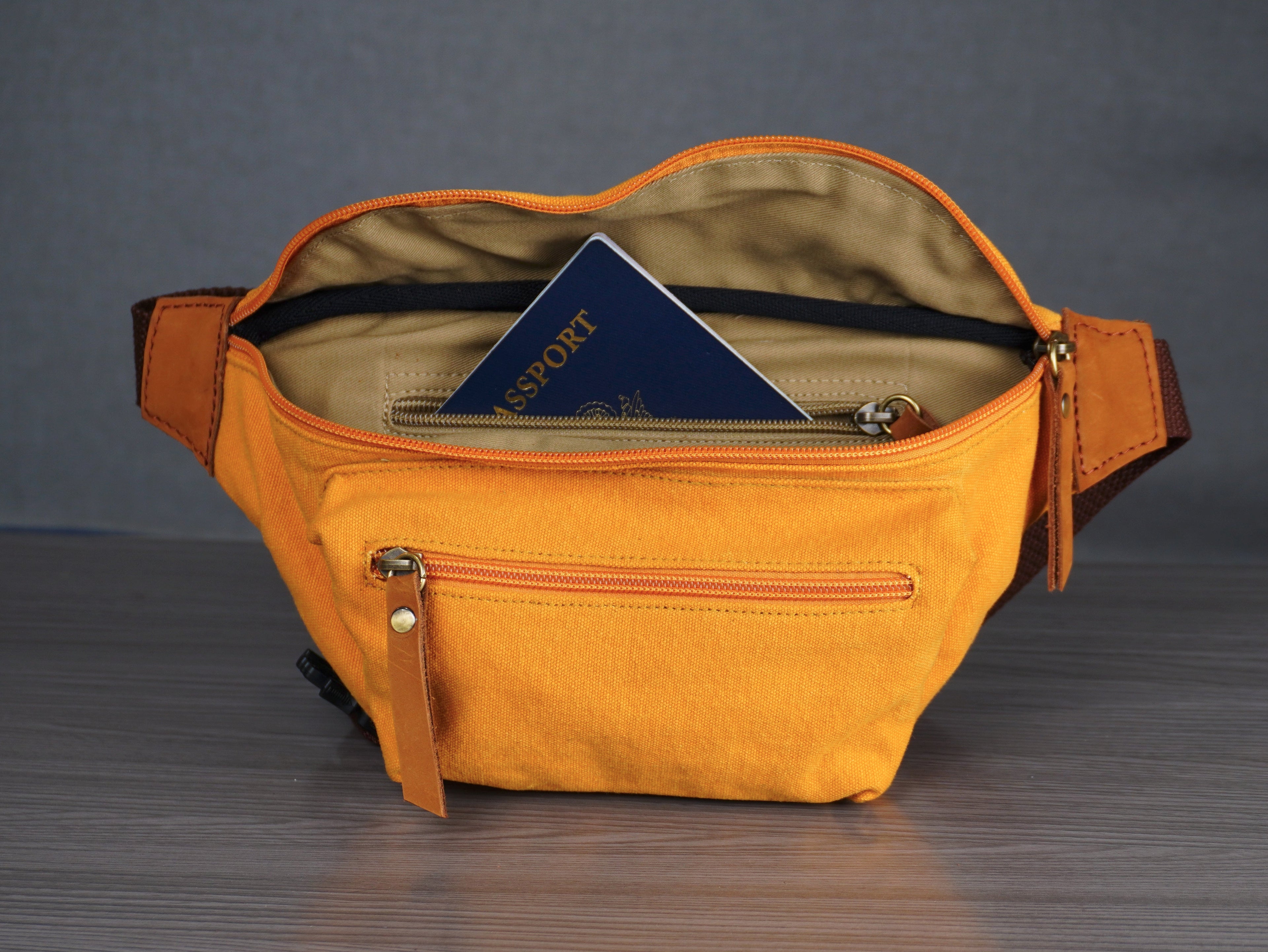 Yellow waist bag with a passport inside on a gray surface