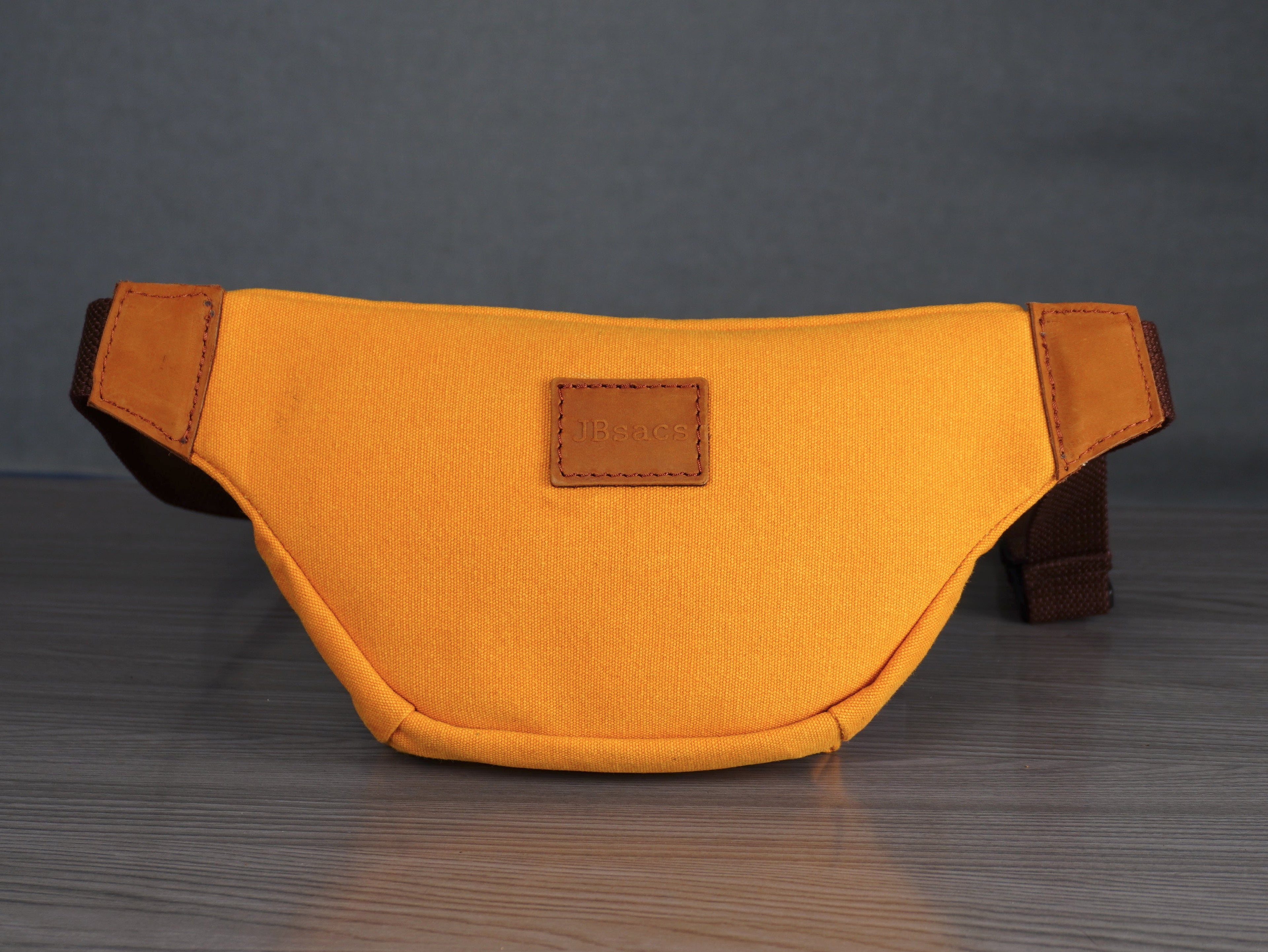 Yellow waist bag with brown accents on a gray surface